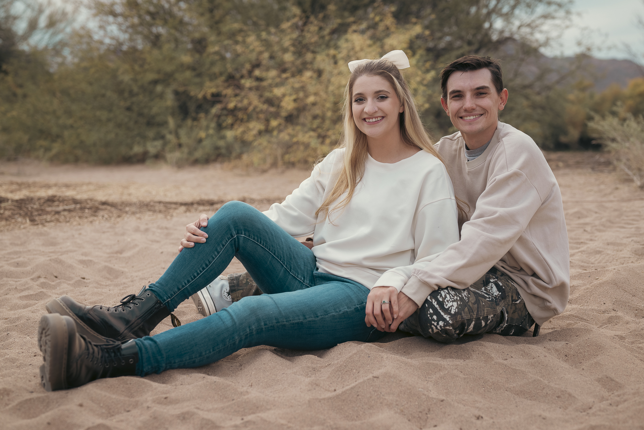 Couple's engagement portrait sitting in the sand at the Lower Salt River