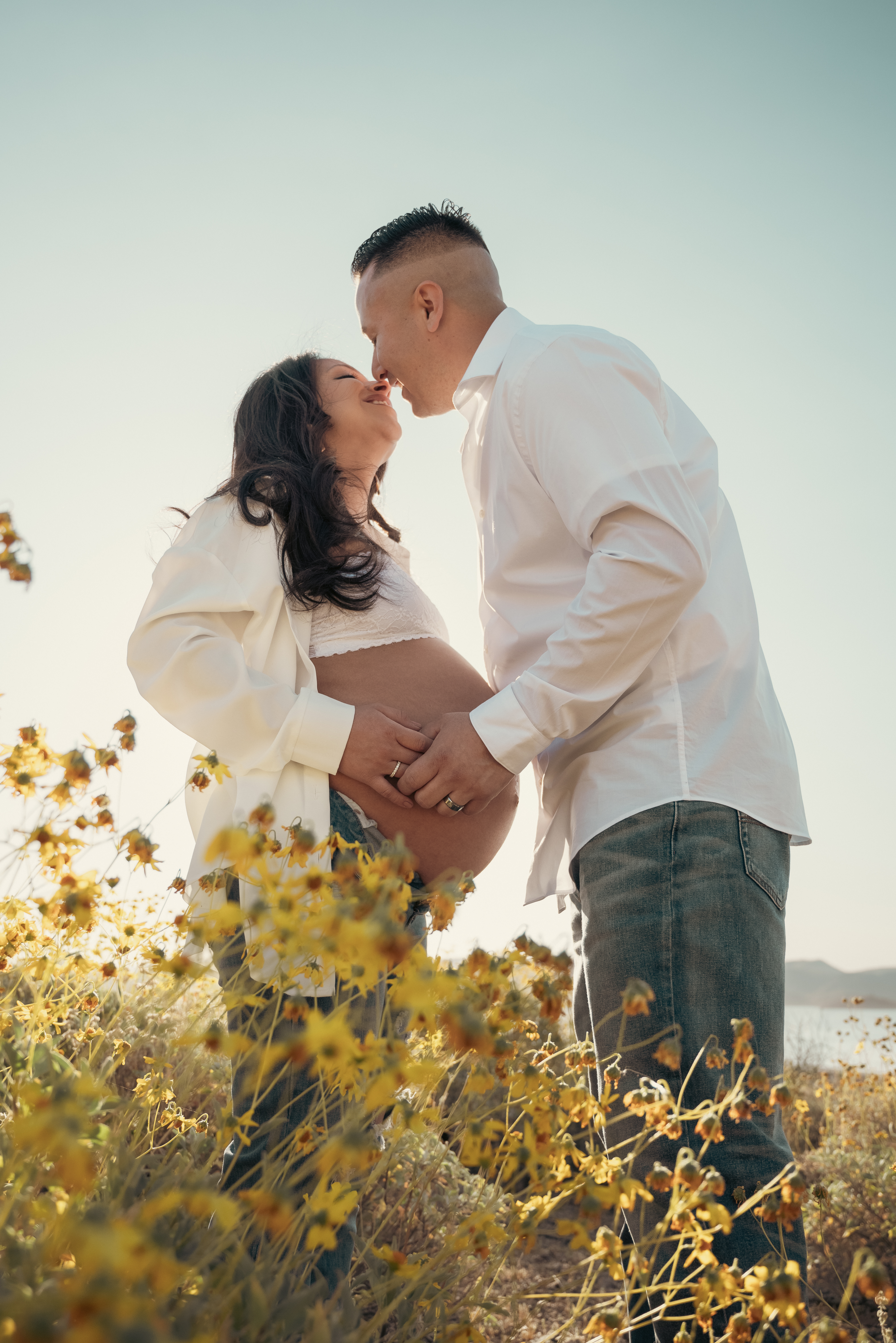 Couple kissing in a field of yellow wildflowers during maternity photo session in Arizona