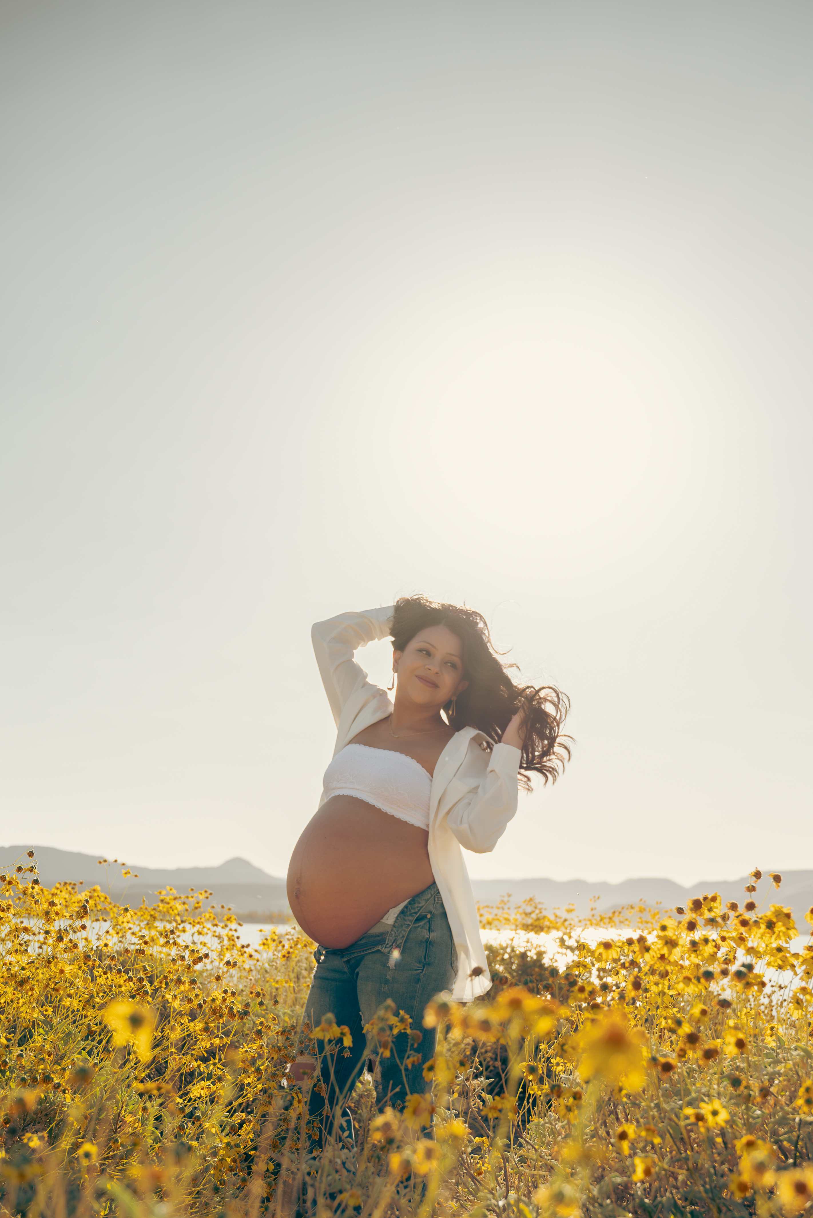 Portrait of pregnant mother dancing in a field of yellow flowers in Arizona