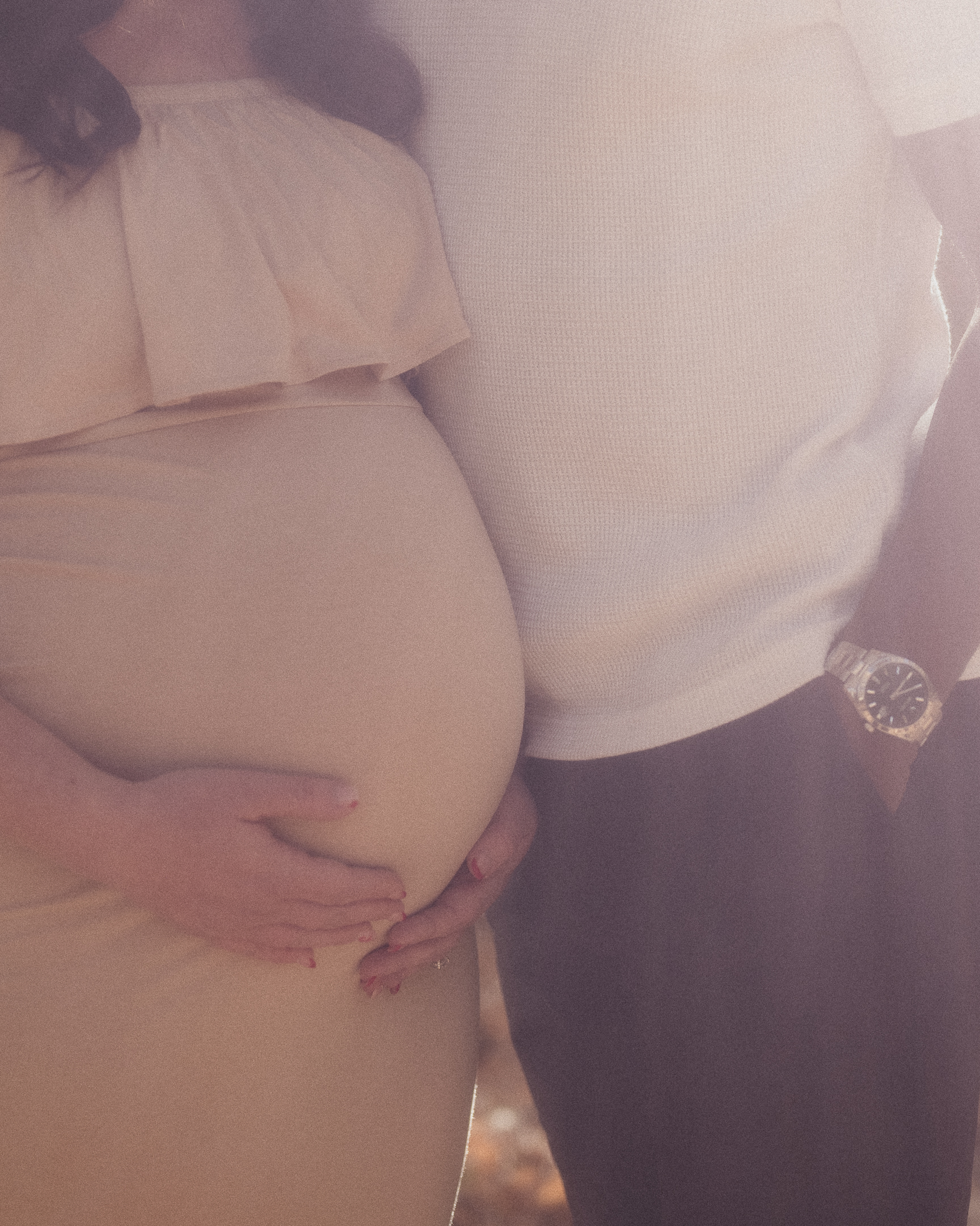 Couple side by side, mother holding her pregnant belly in dreamy lighting