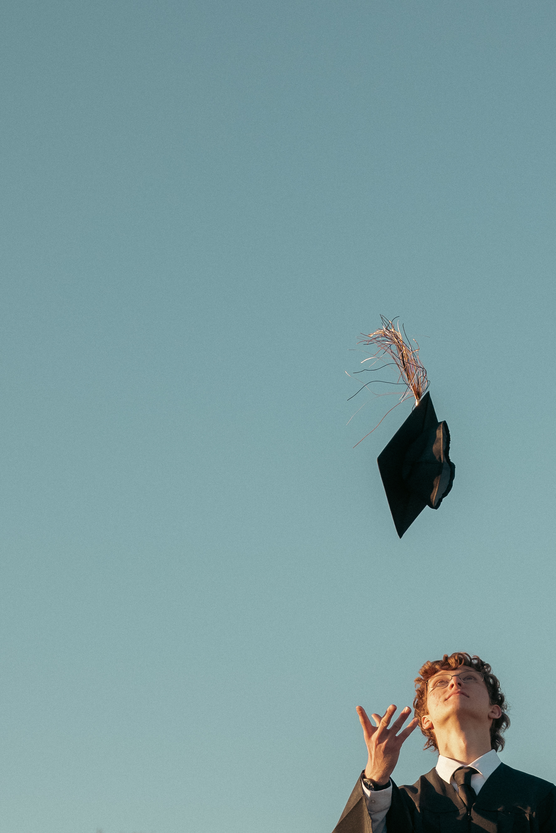 Senior photo of young man tossing graduation cap in the air