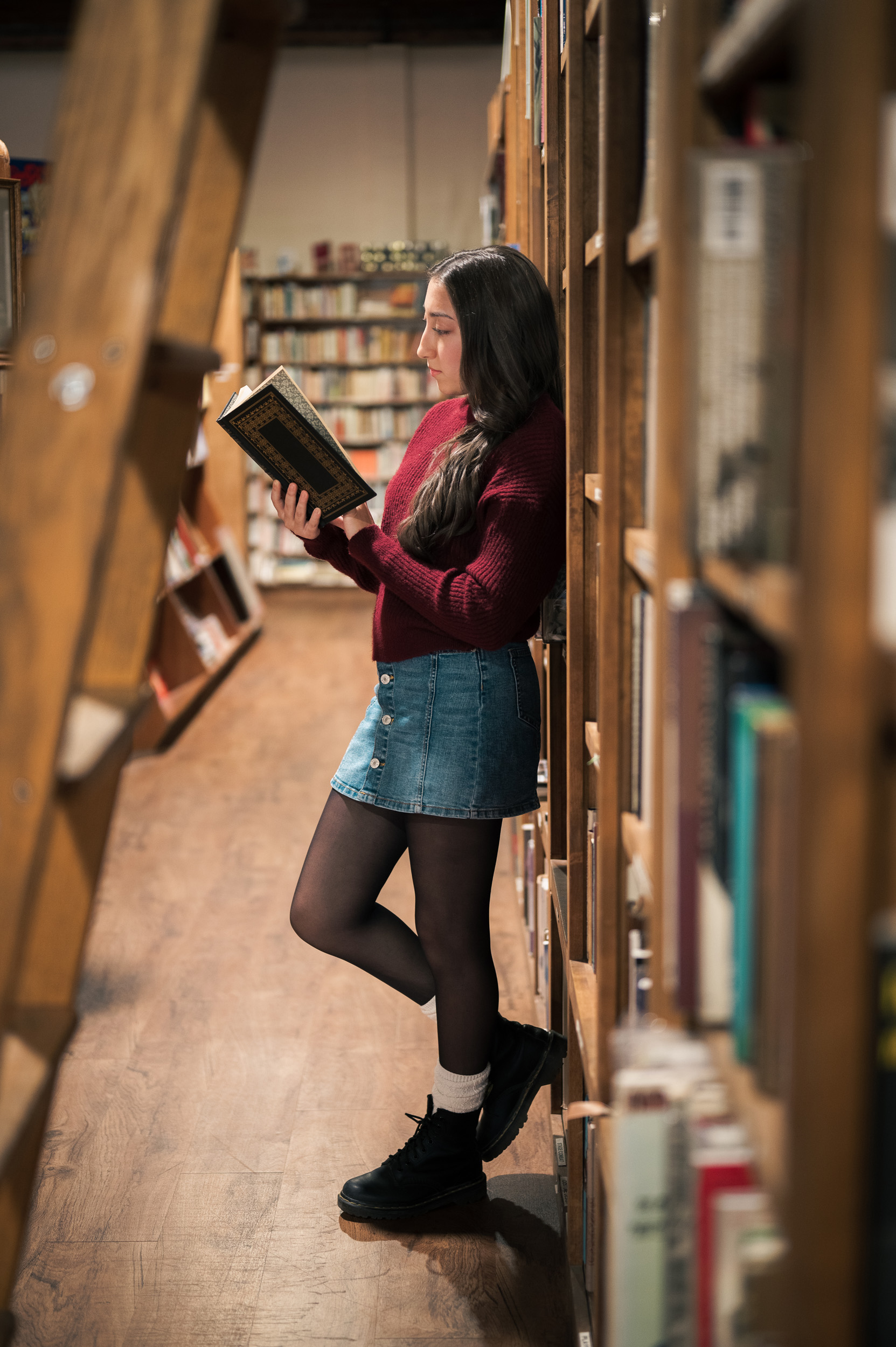 Senior Portrait leaning against bookshelves reading at Phoenix Arizona Book Gallery.