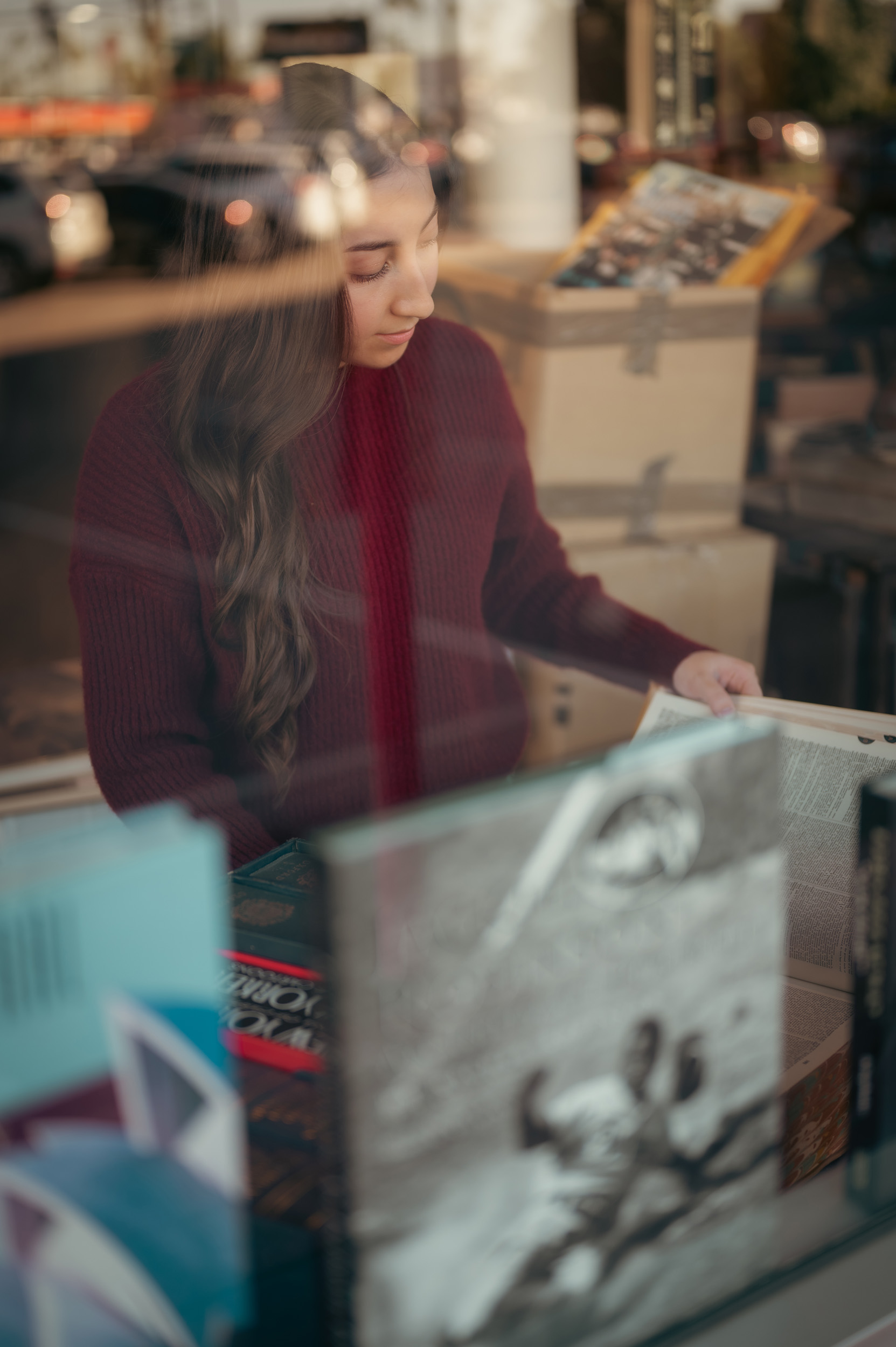 Portrait through shop window of girl reading at Phoenix Book Gallery.