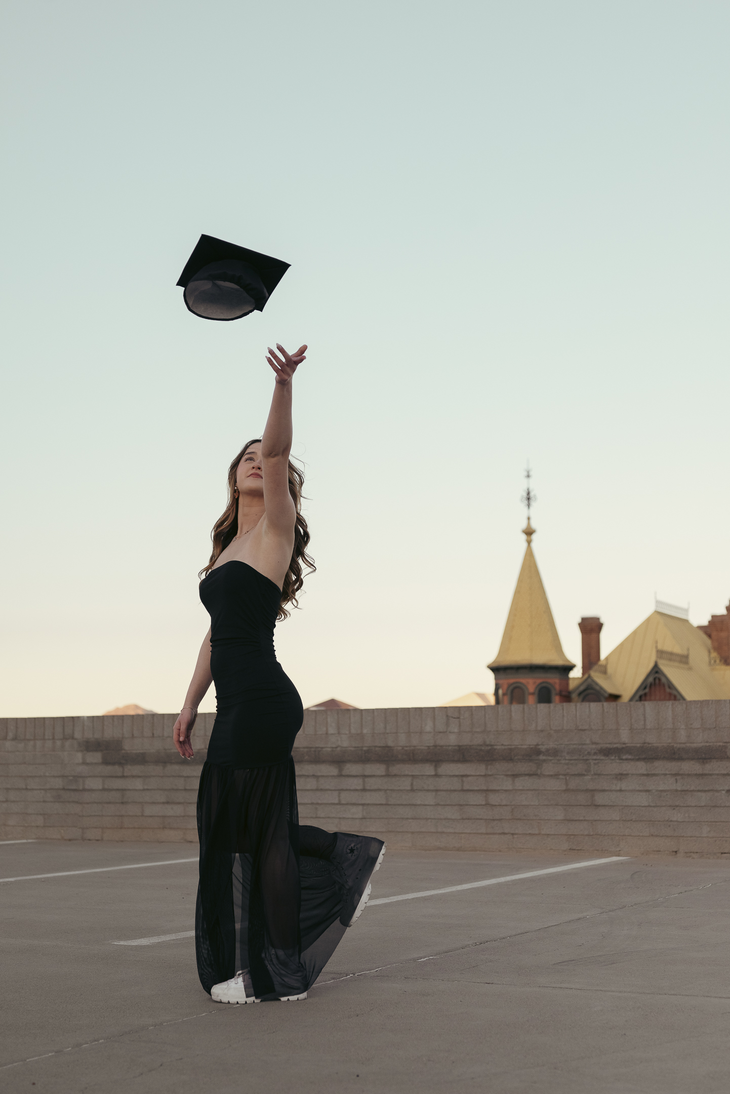 Senior photo of young lady tossing graduation cap in the air