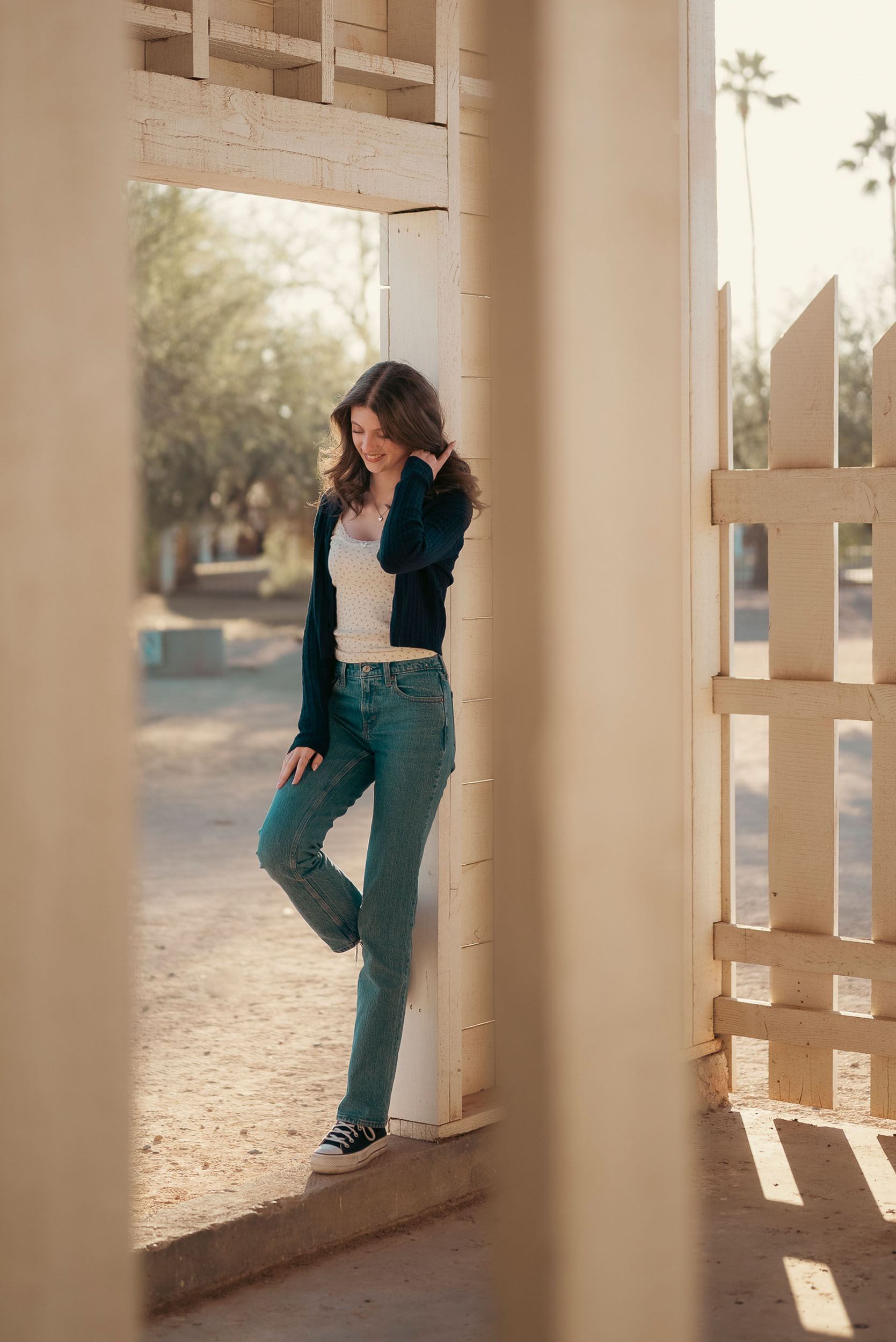 Senior photo of young woman taken in door frame of farm house in Sahuaro Ranch Park in Glendale, AZ.