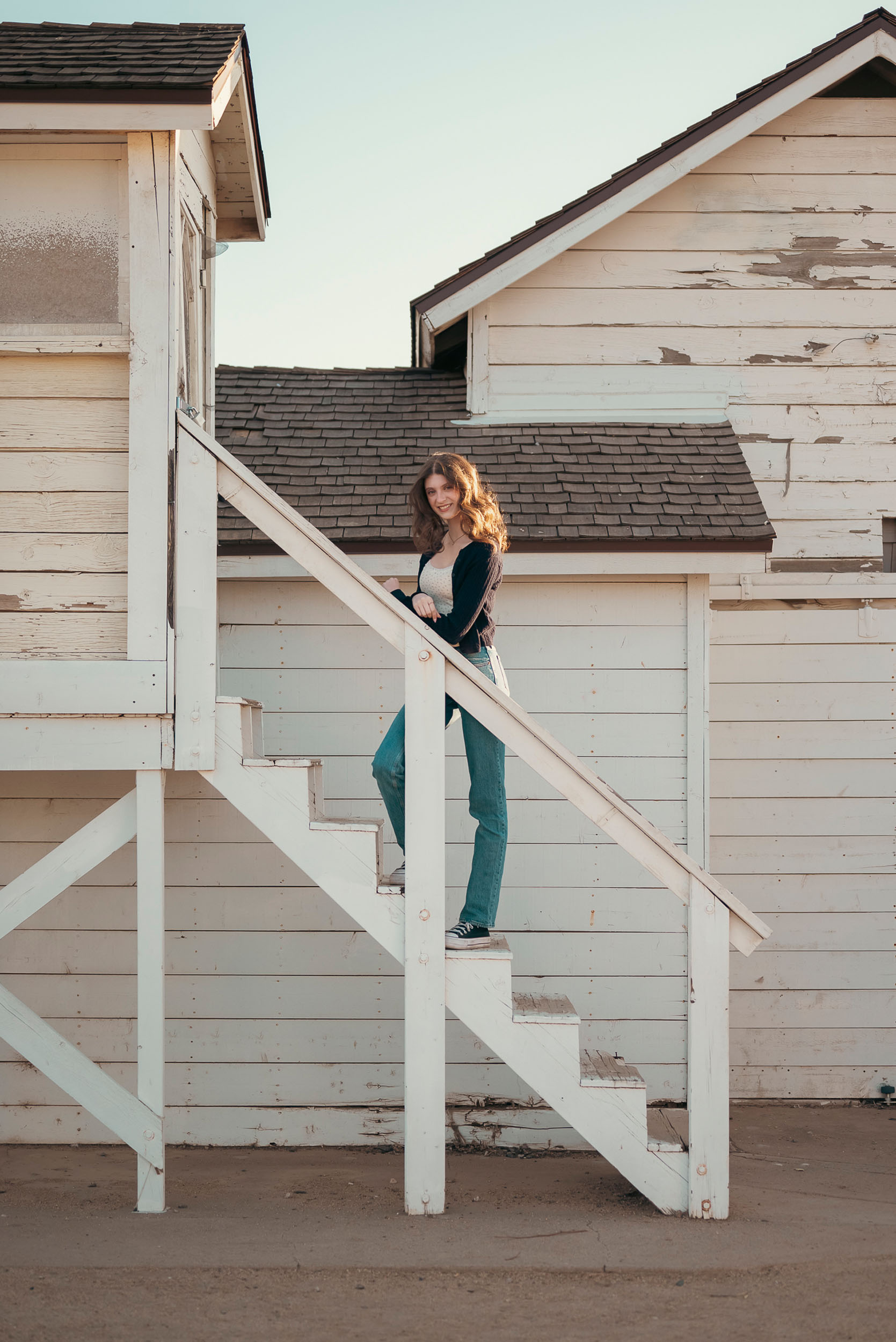 Senior photo of young woman taken on stairs of farm house in Sahuaro Ranch Park in Glendale, AZ.