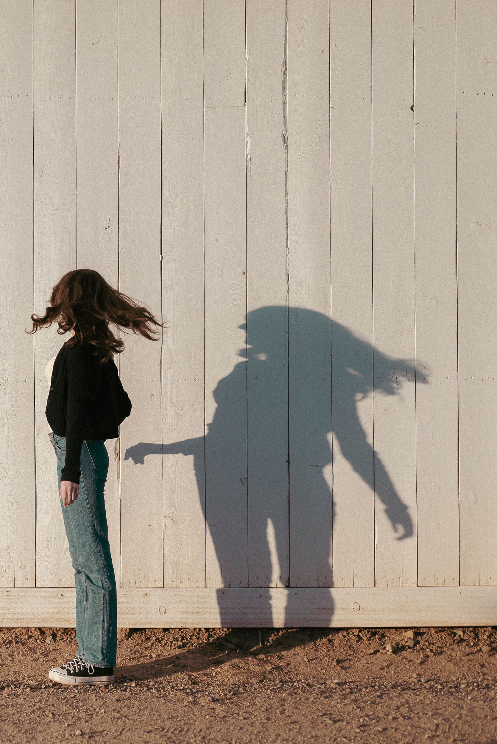 Senior photo of young woman with shadow cast on farm house in Sahuaro Ranch Park in Glendale, AZ.