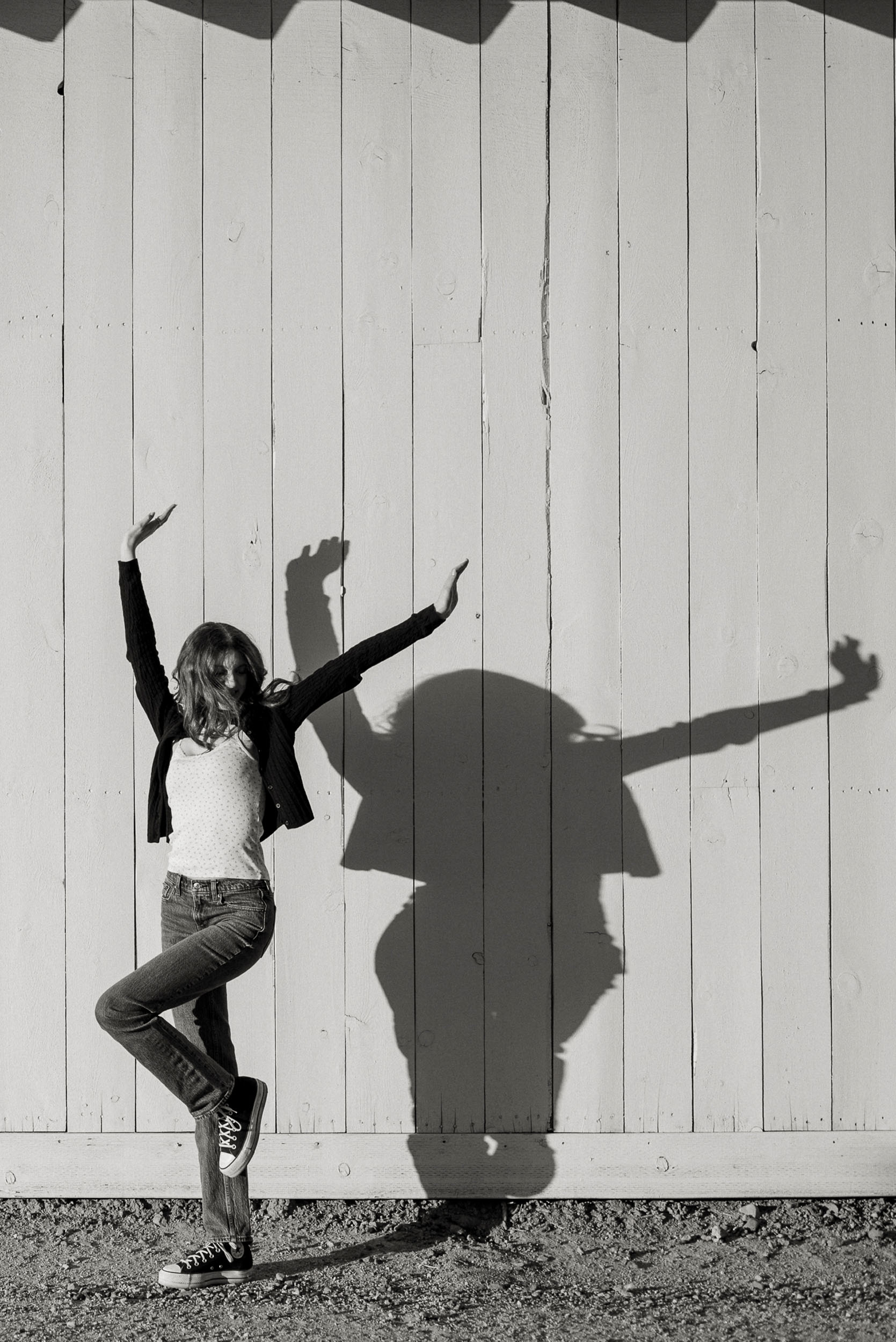 Senior photo of young woman with shadow cast on farm house in Sahuaro Ranch Park in Glendale, AZ.
