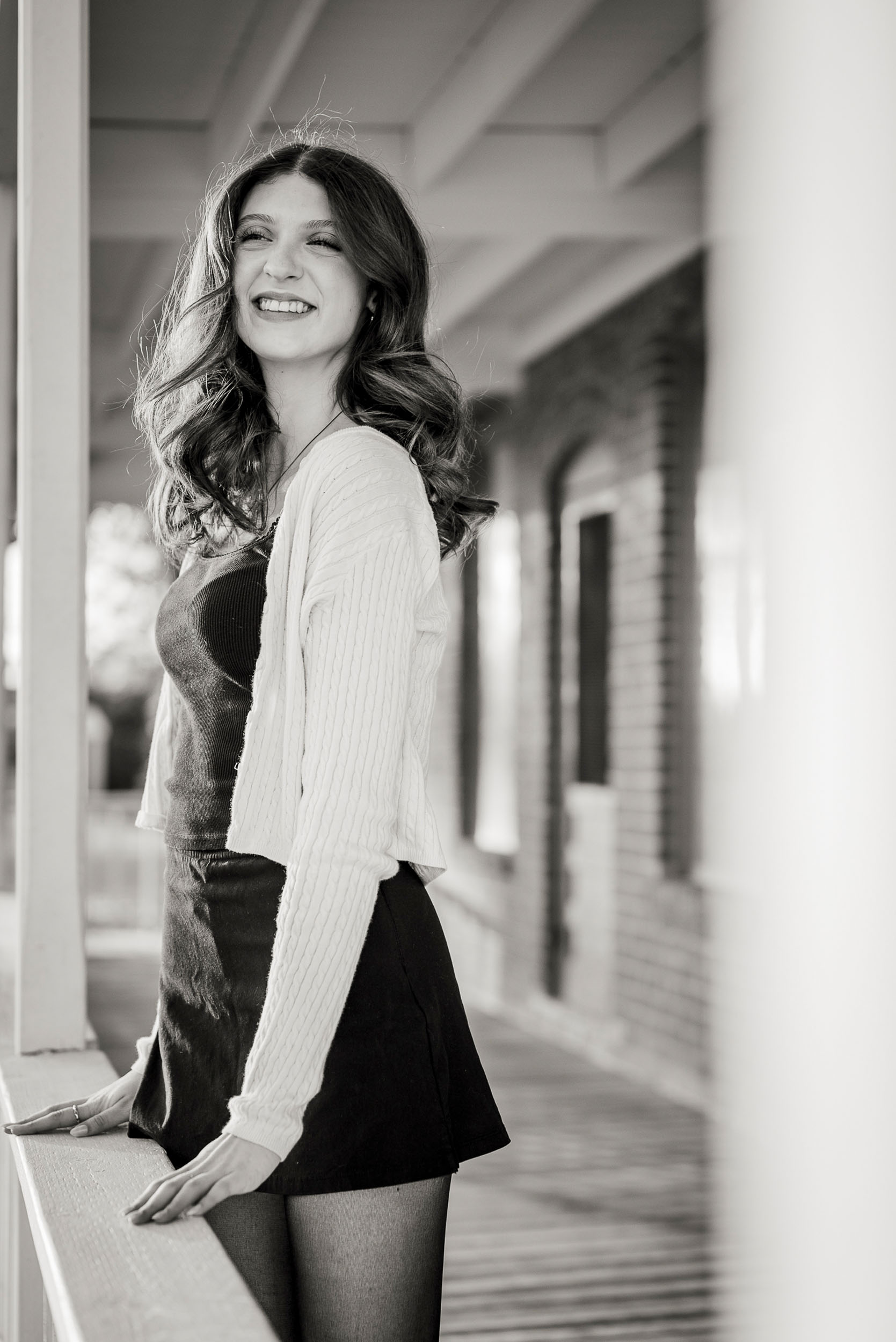 Senior photo of young woman on porch of farm house in Sahuaro Ranch Park in Glendale, AZ.