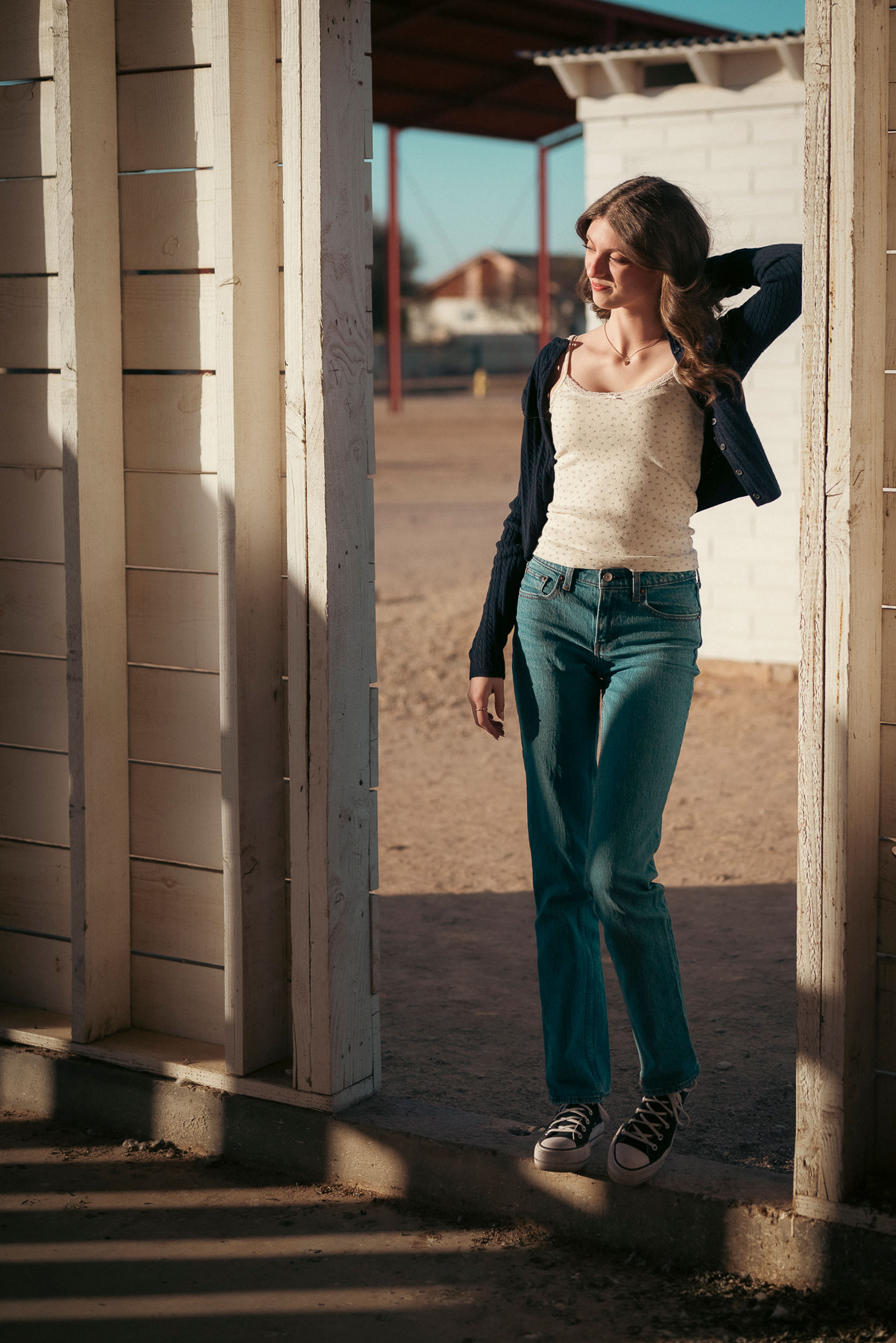 Senior photo of young woman taken in door frame of farm house in Sahuaro Ranch Park in Glendale, AZ.