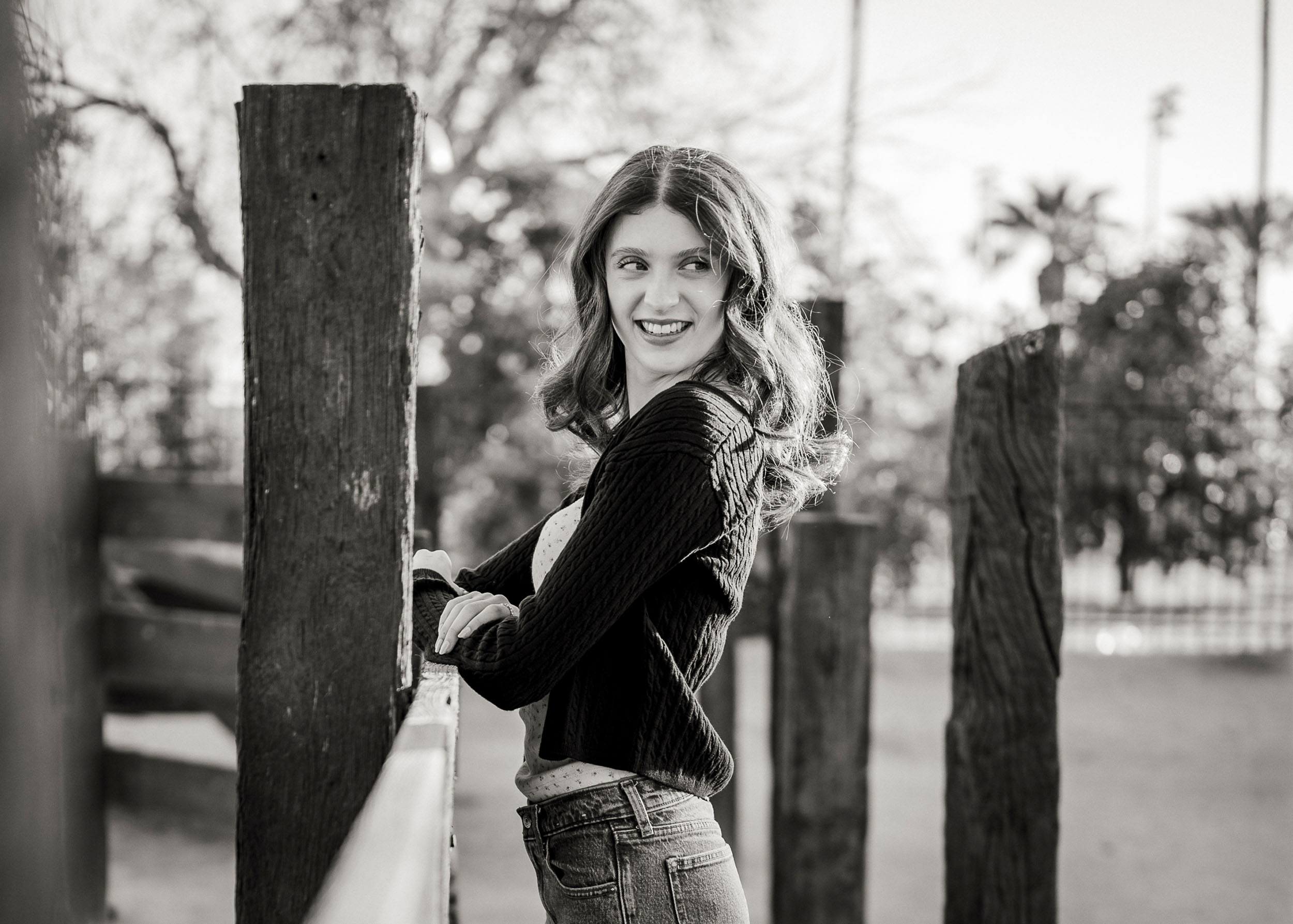 Senior photo of young woman leaning on wooden fence at Sahuaro Ranch Park Glendale, AZ.