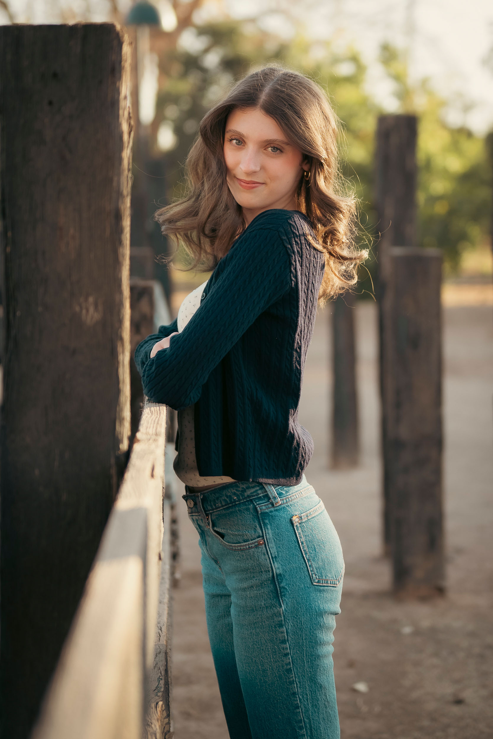 Senior photo of young woman leaning on wooden fence at Sahuaro Ranch Park Glendale, AZ.