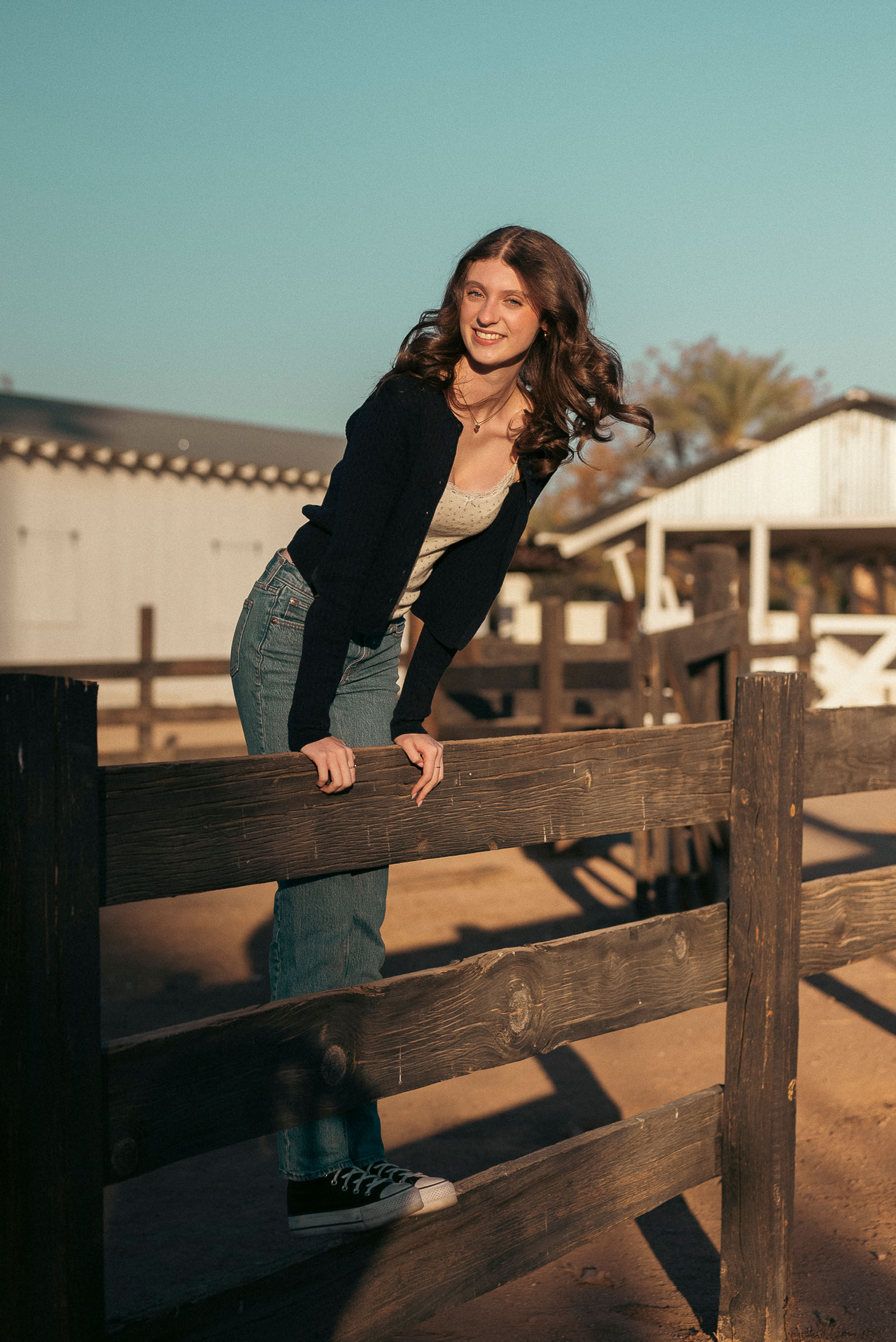 Senior photo of young woman leaning on wooden fence at Sahuaro Ranch Park Glendale, AZ.