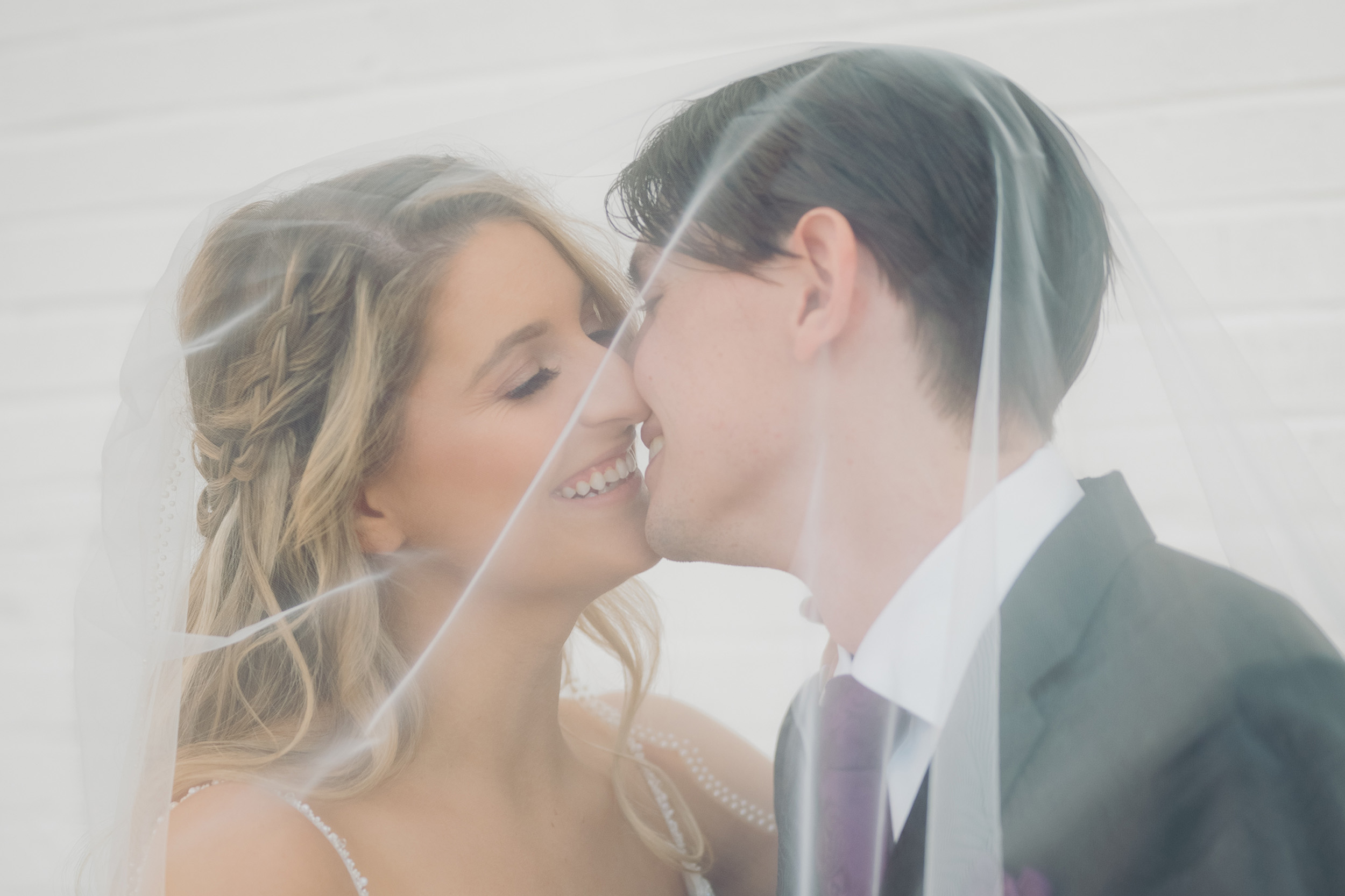 bride and groom kissing framed by wedding veil.