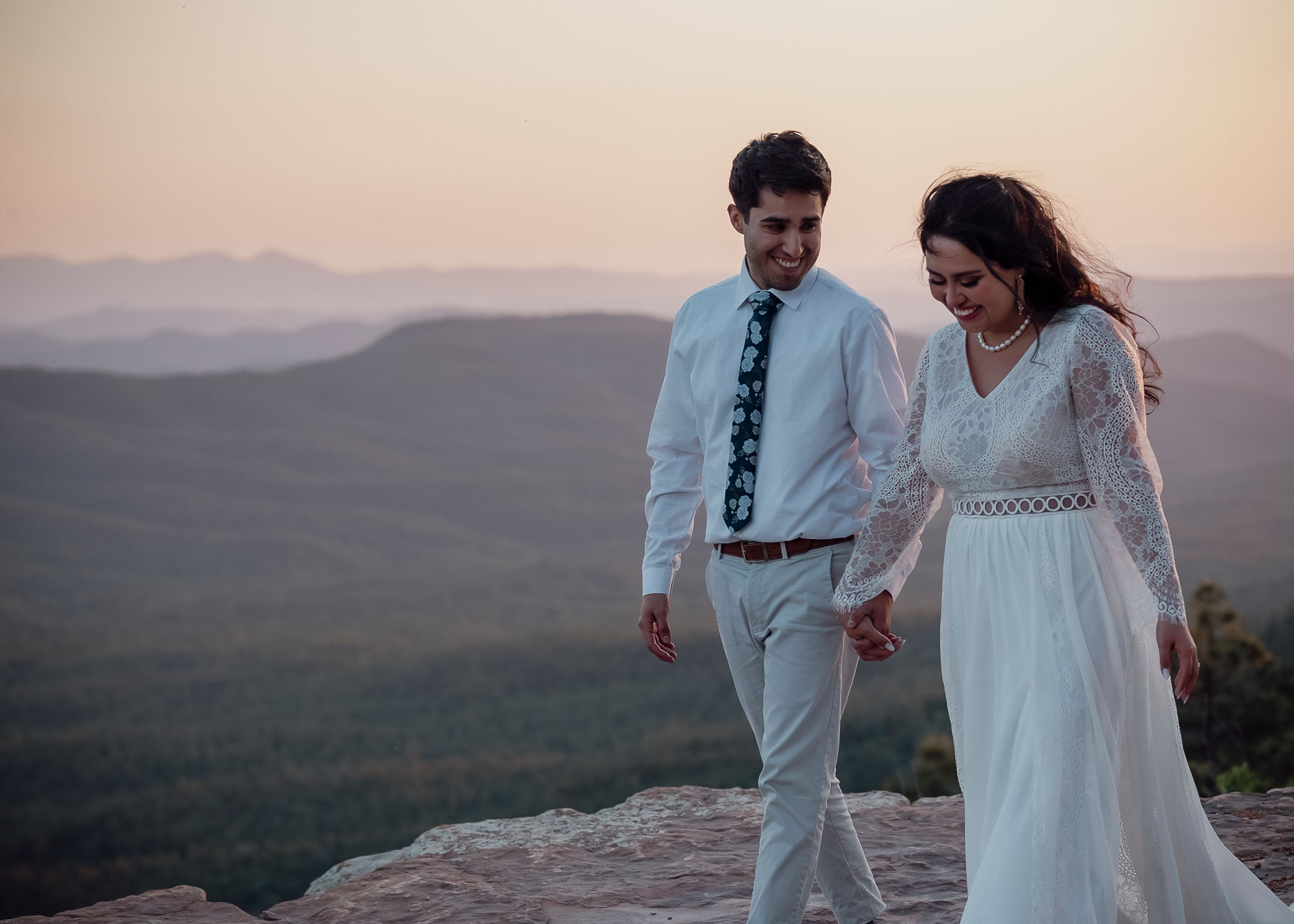 Bride and groom holding hands cliffside during elopement wedding at the Mogollon Rim in Payson, Arizona