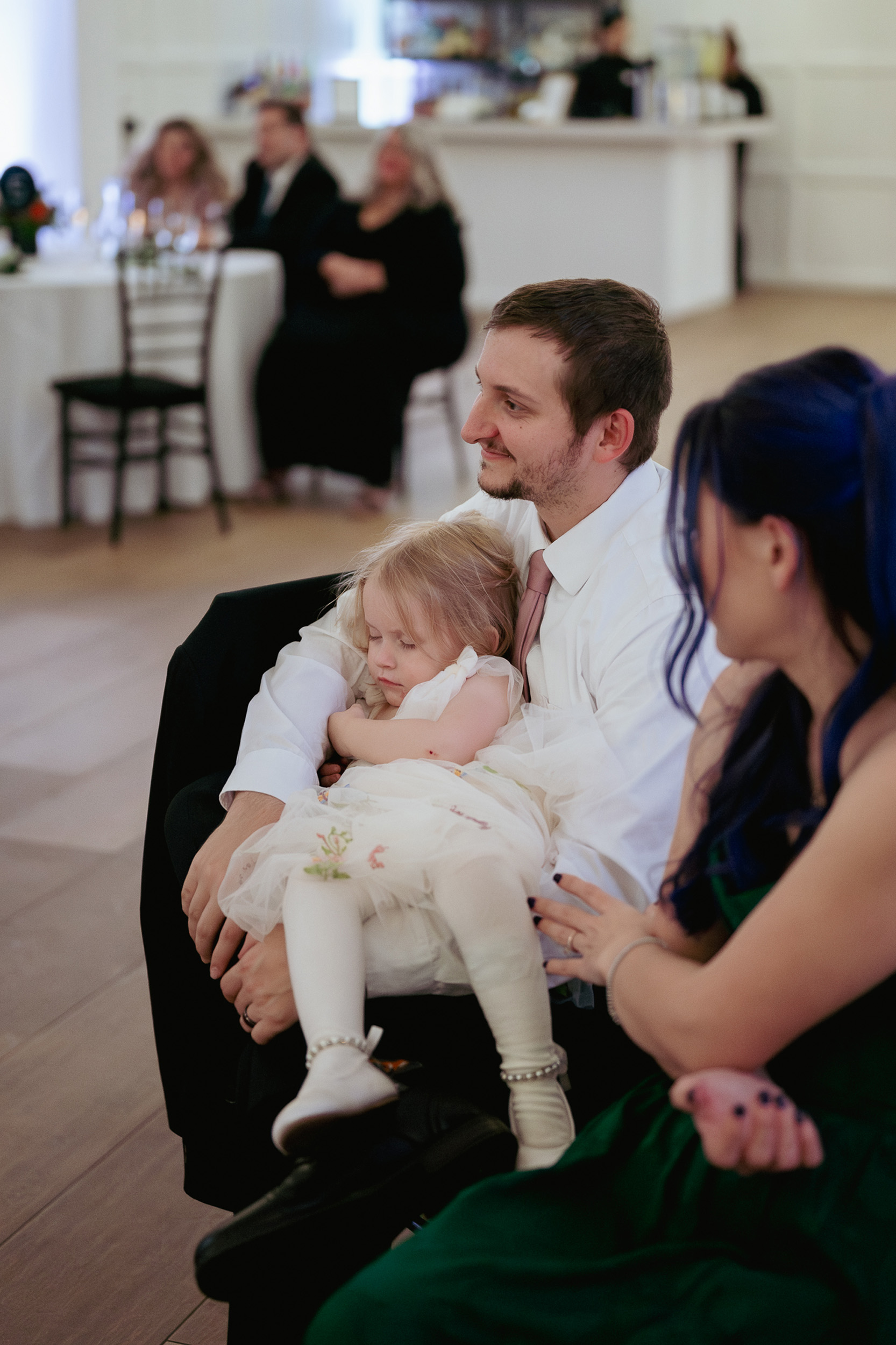 wedding guests listen to speeches while child sleeps in arms at reception at Tre Bella Mesa Arizona.