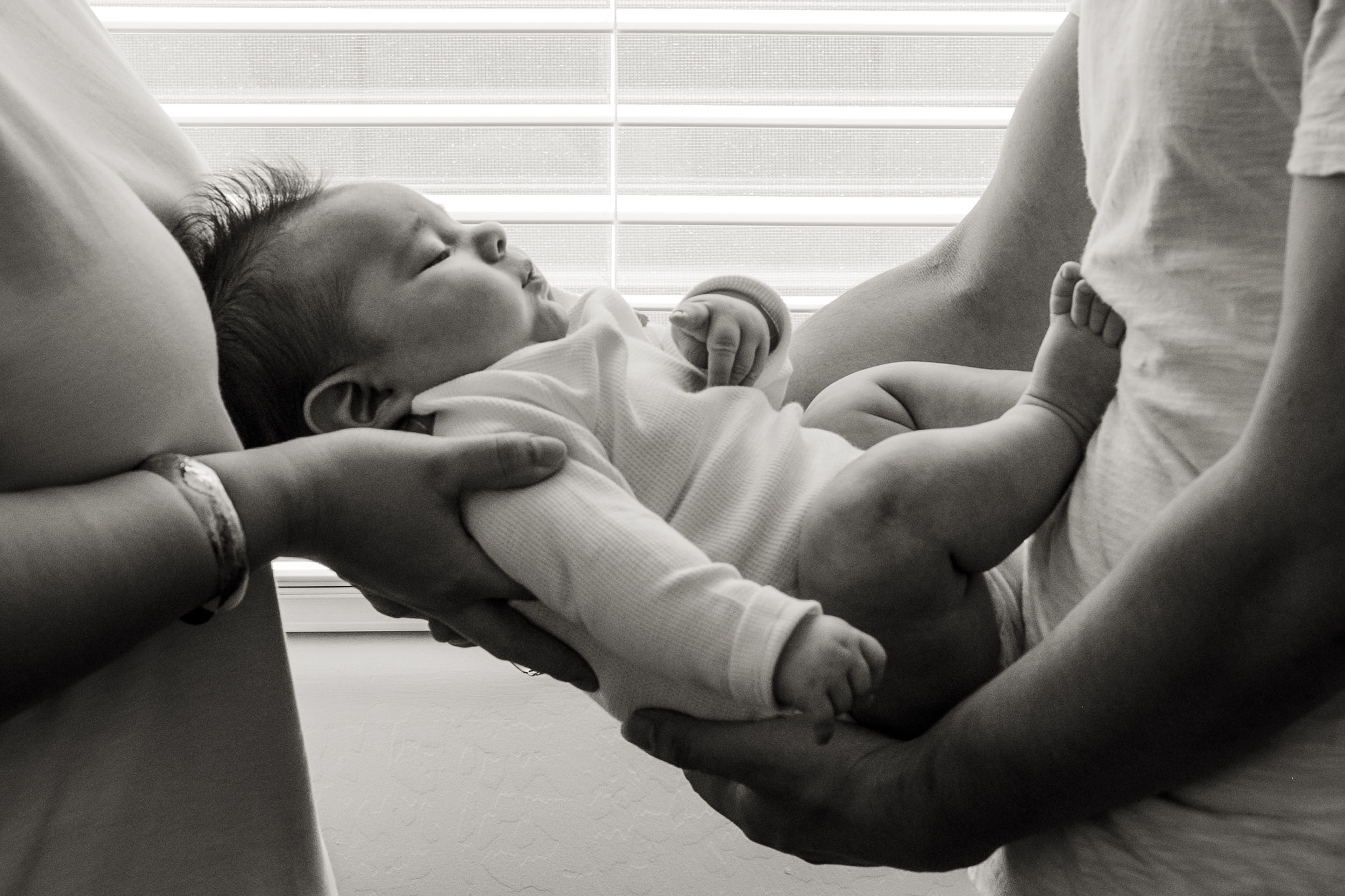 mother and father holding newborn baby between them during lifestyle photo session in Arizona