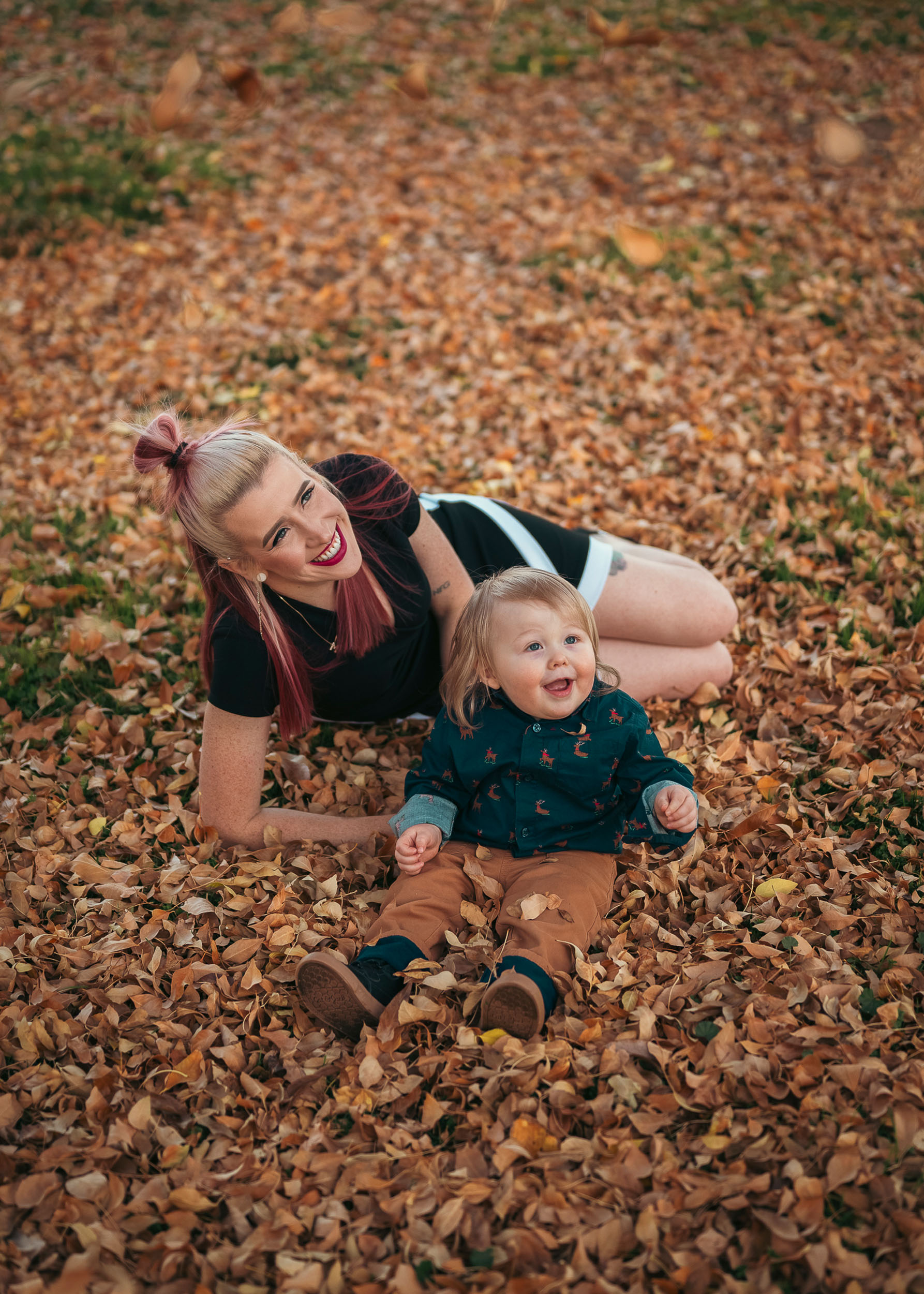 Mother and toddler son laying in a patch of fall autumn leaves in Marley Park Surprise