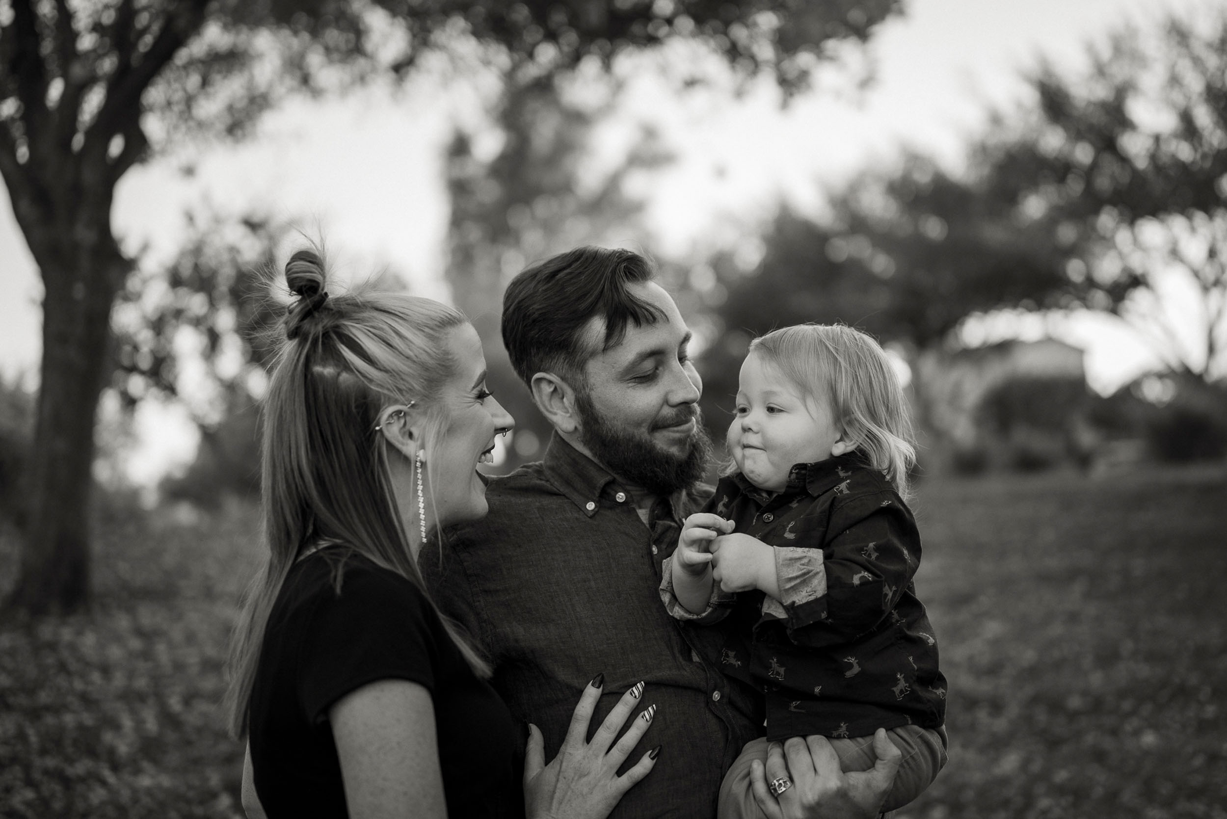 black and white photo of parents holding toddler son smiling and admiring lovingly