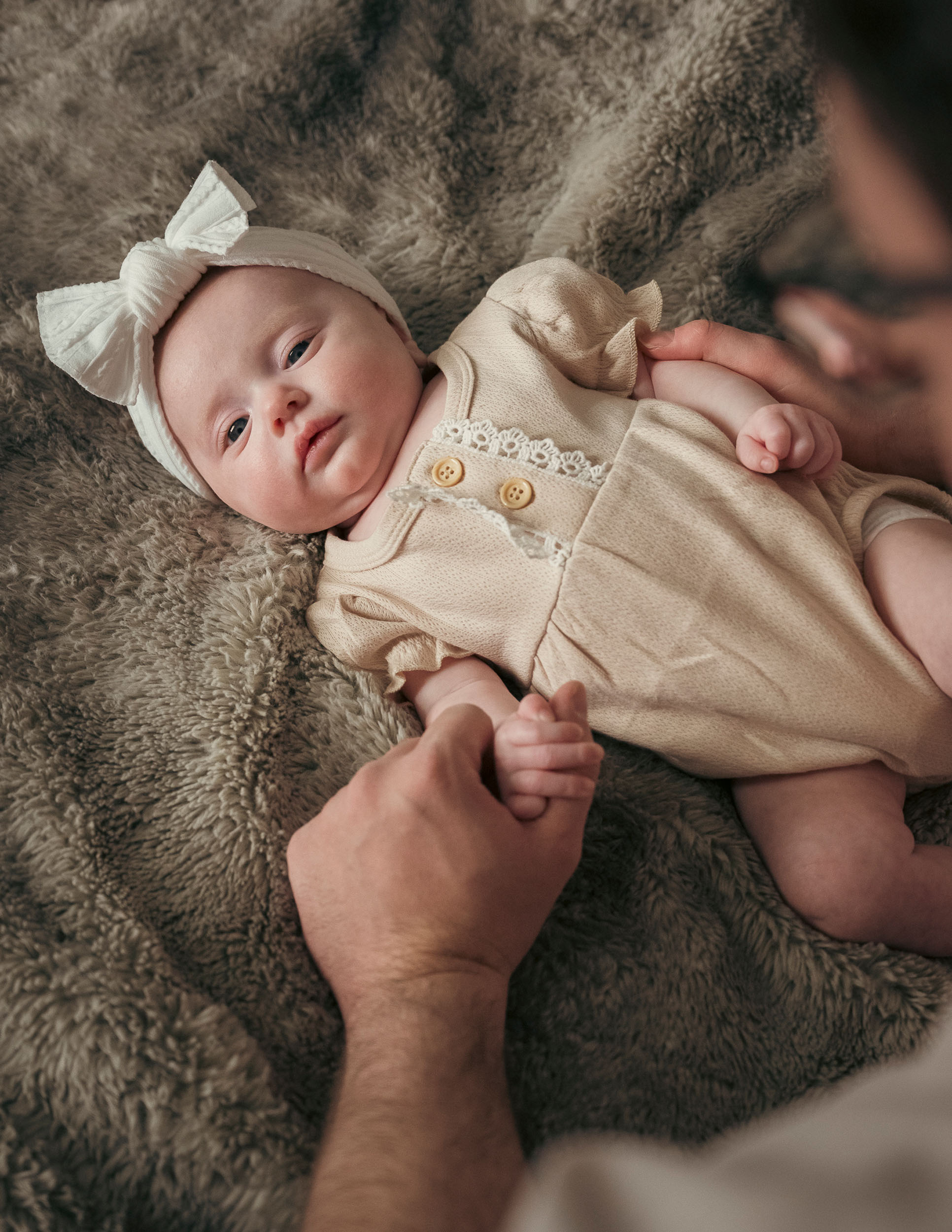 father holding hand of newborn baby during family photo session