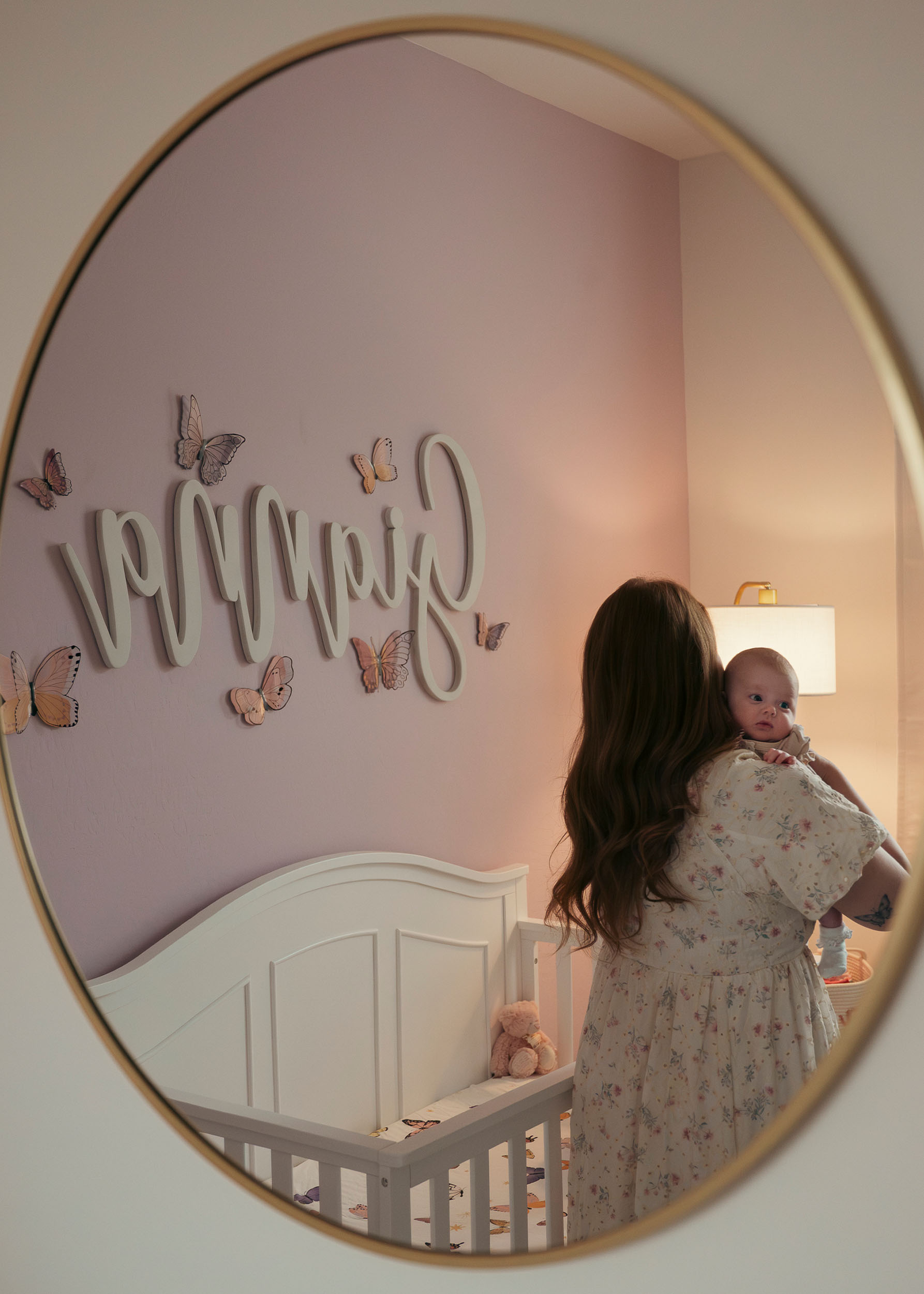 mirror reflection showing mother holding baby by crib
