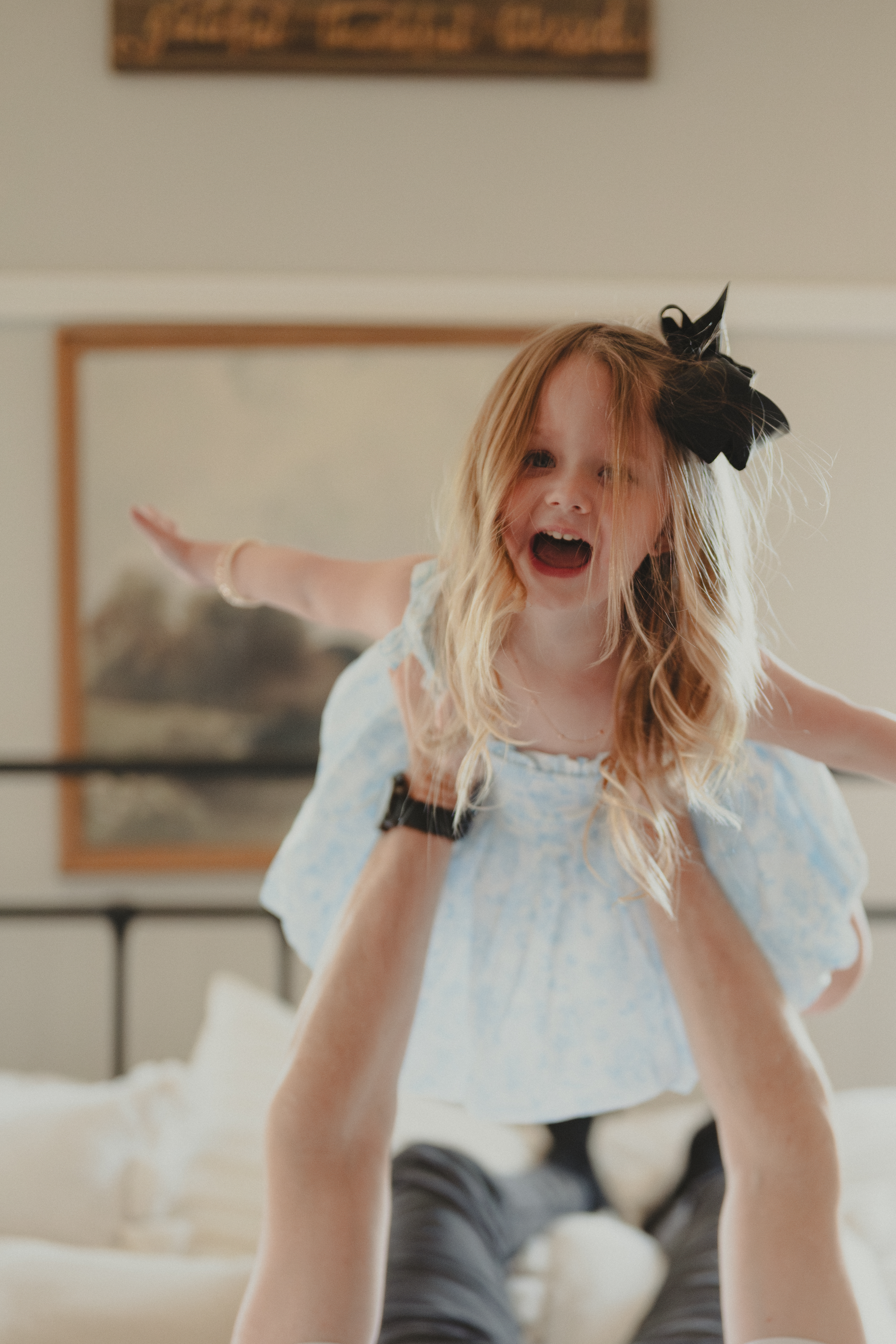 Young girl being held by dad engaging in horse play in Lifestyle family portraits.