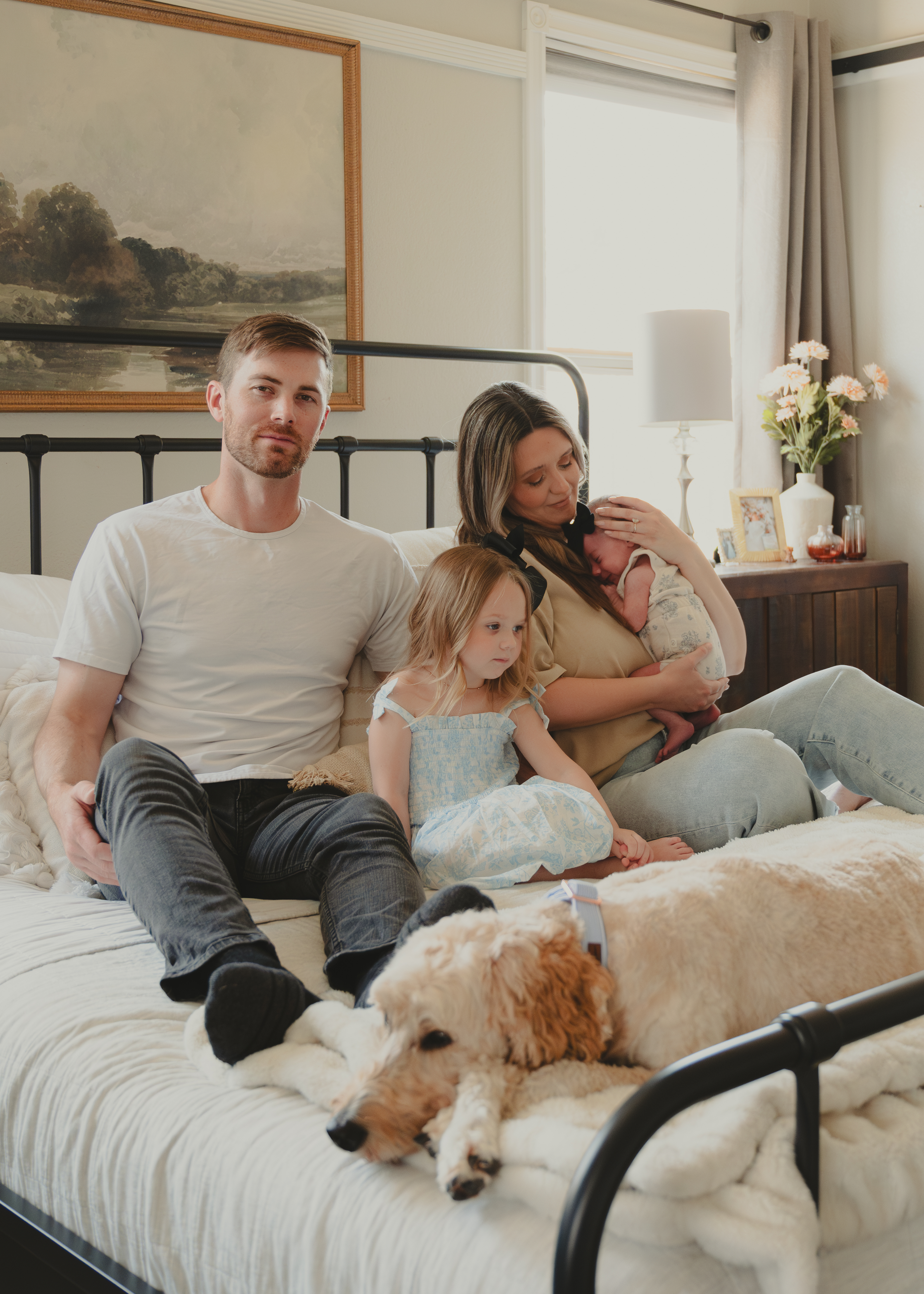 Family sitting together on their bed with their newborn  baby for Lifestyle family portraits.