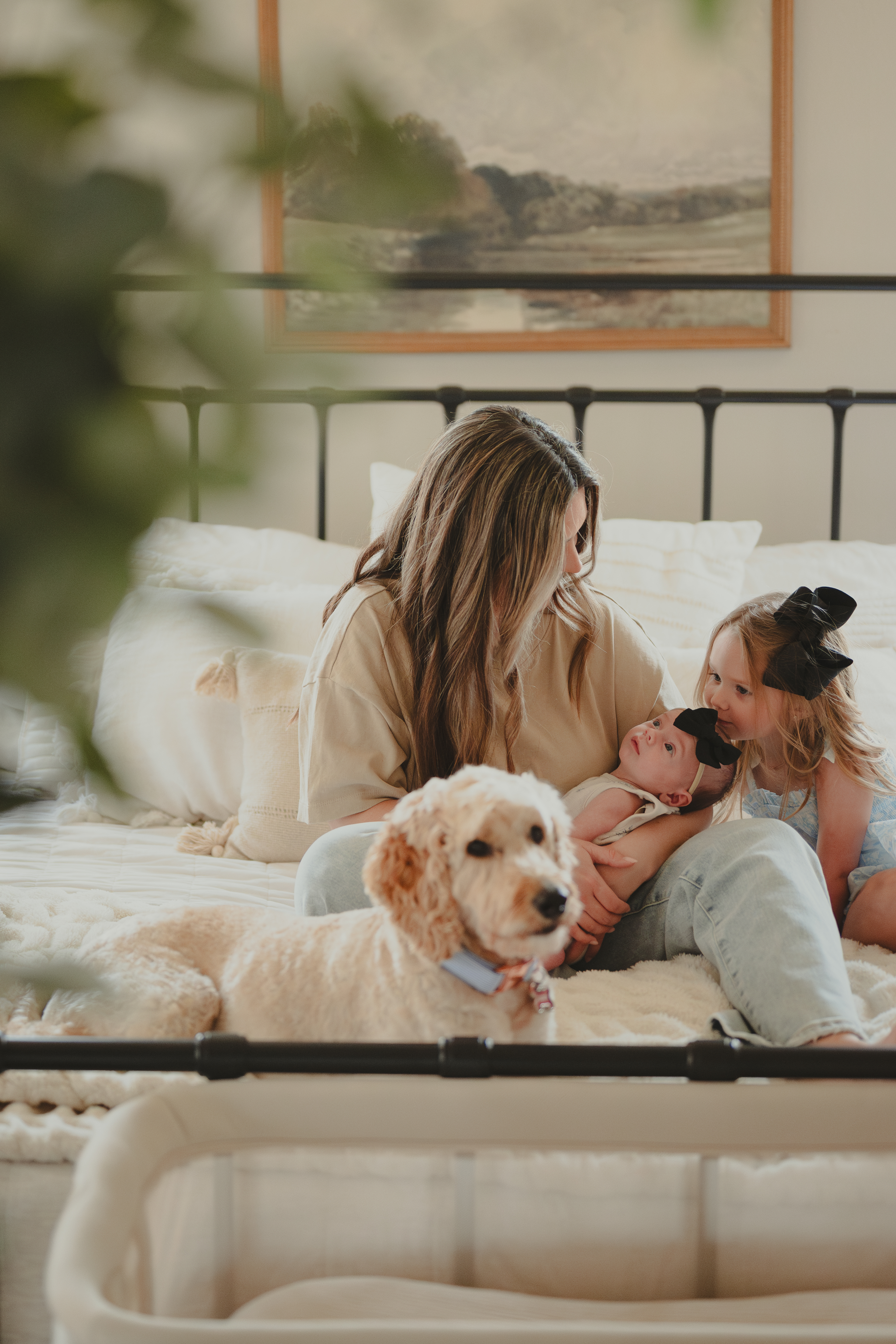 Family sitting together on their bed with their newborn  baby for Lifestyle family portraits.