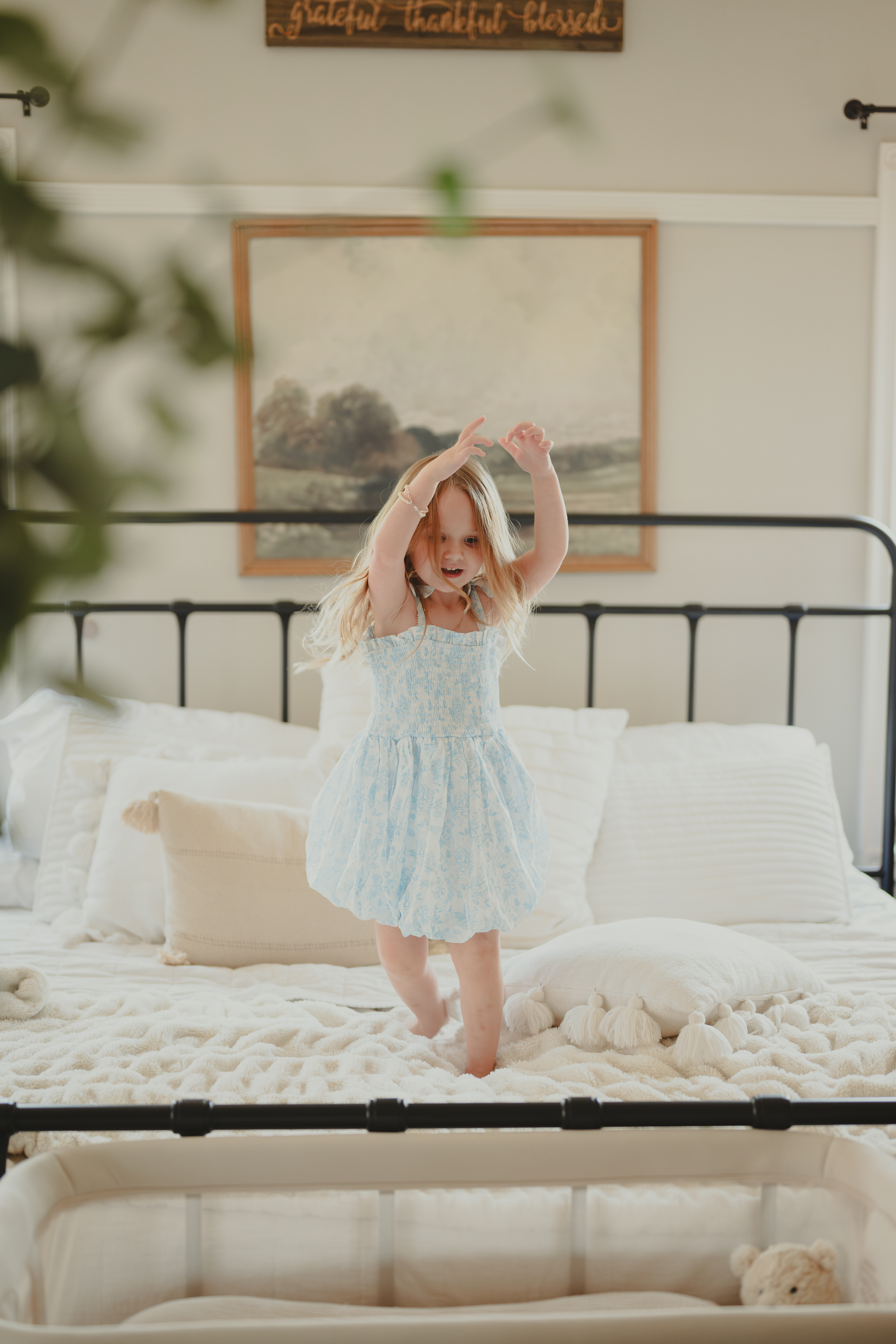 Young girl jumping on bed for Lifestyle family portraits.