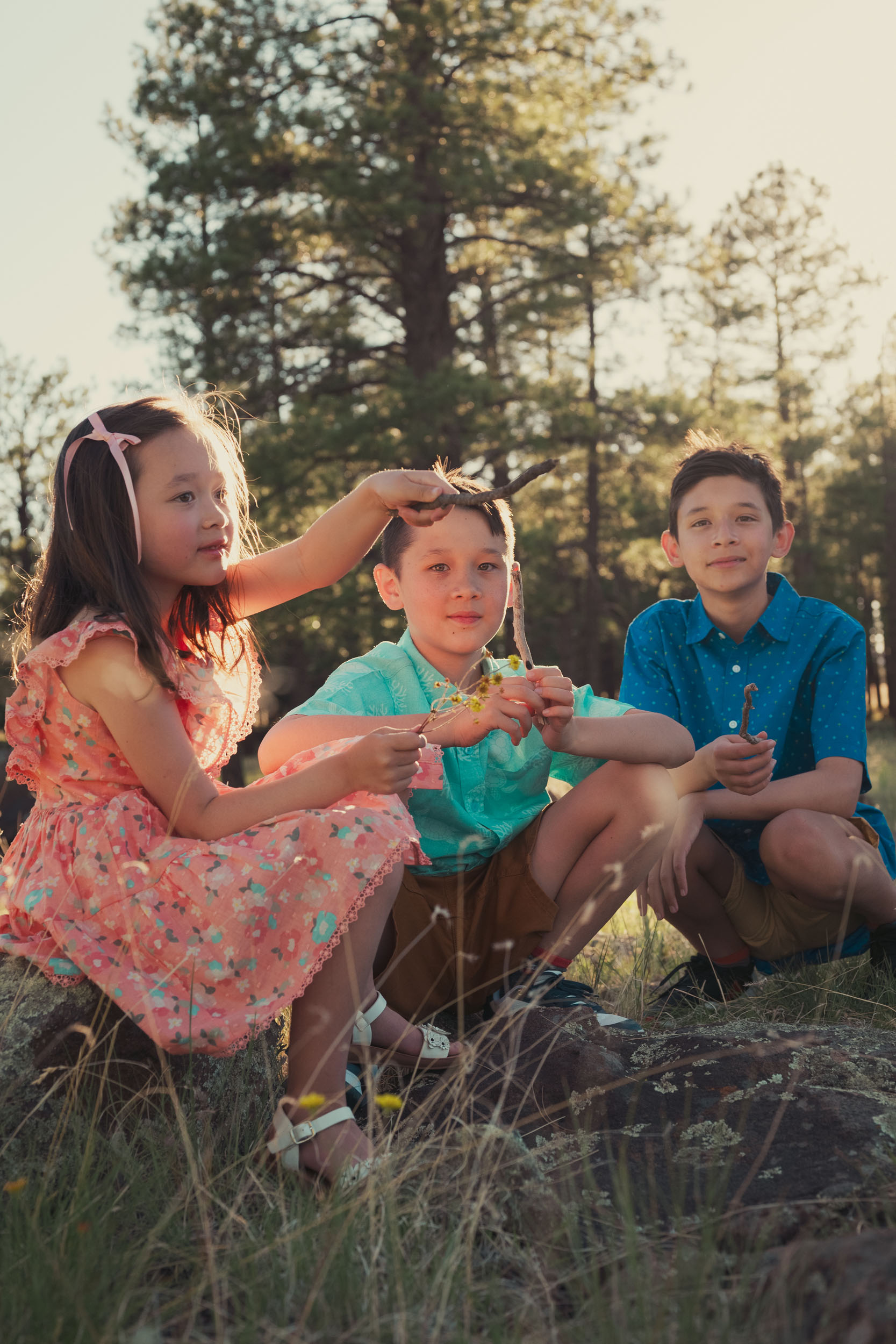children siblings sitting in the forest playing with sticks