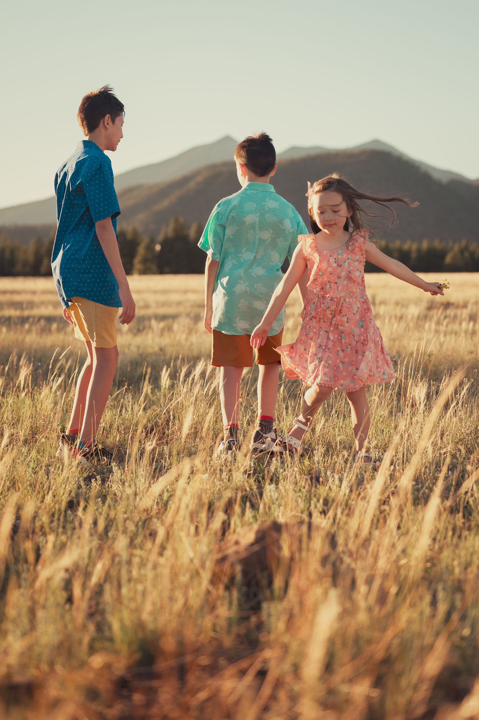 children playing in grassy meadow at golden hour with Mt. Humphreys in the background