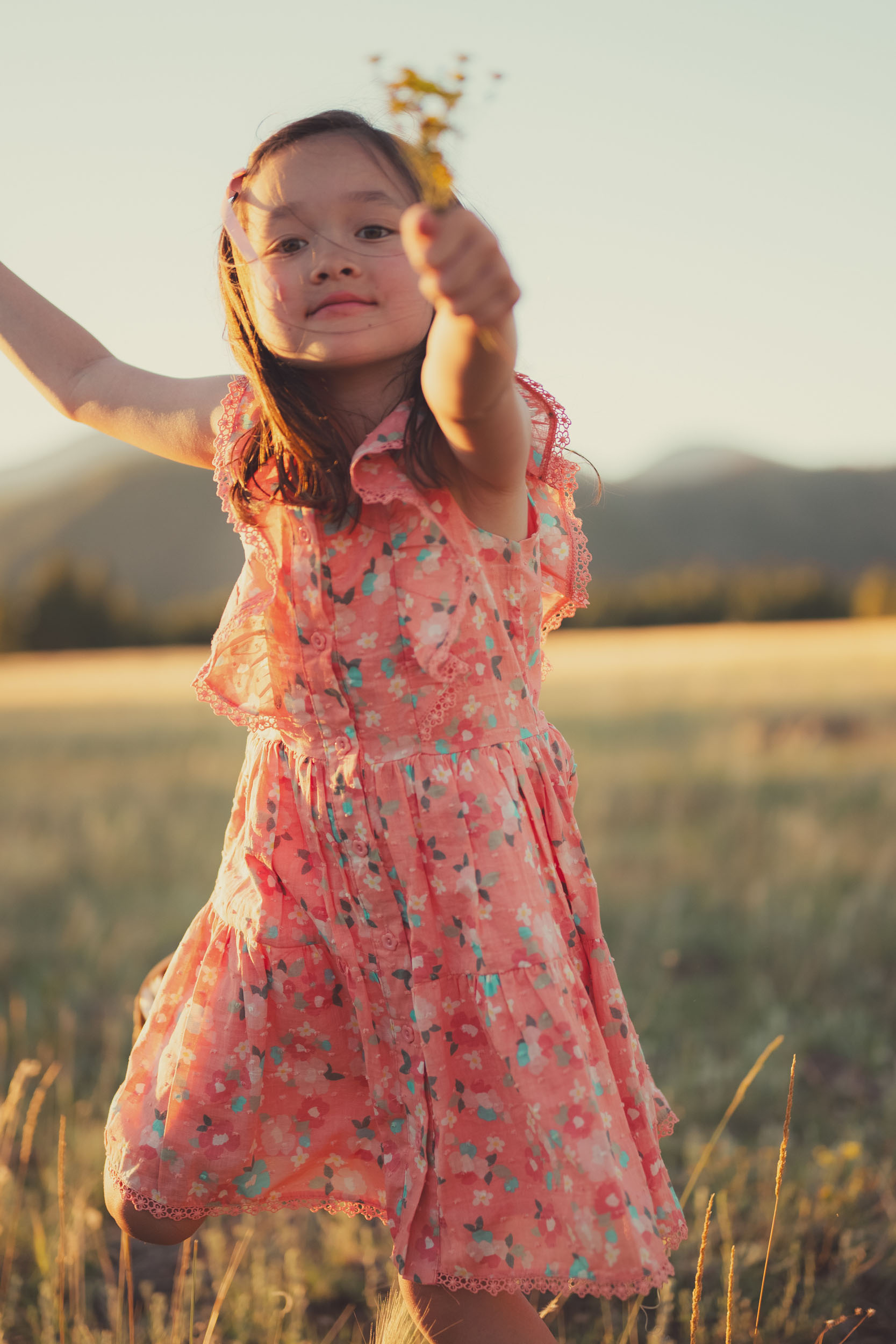 young girl frolicking in the meadow holding wildflowers at golden hour