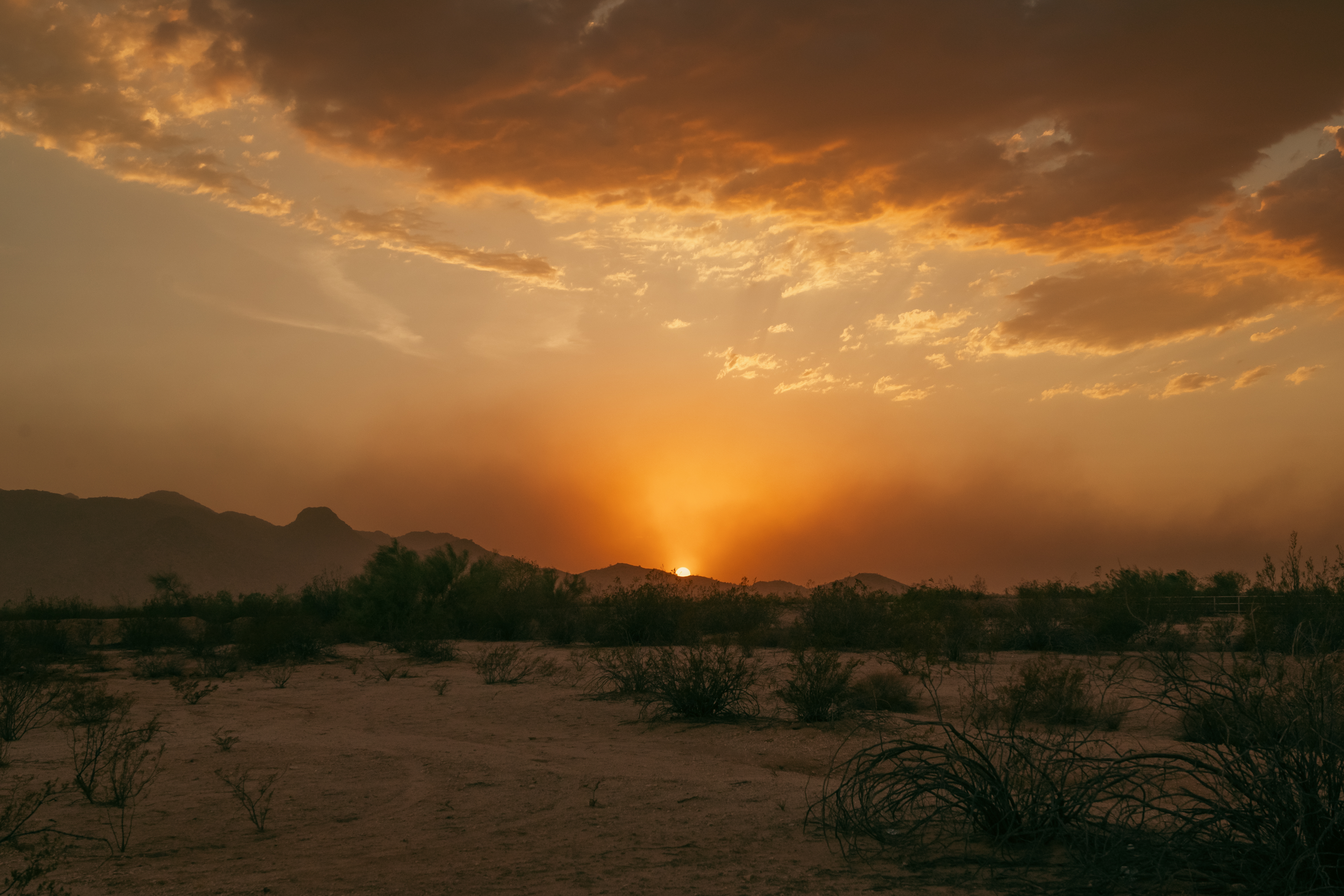 Dusty, hazy monsoon blowing over valley at sunset by White Tank Mountain Regional Park Arizona.