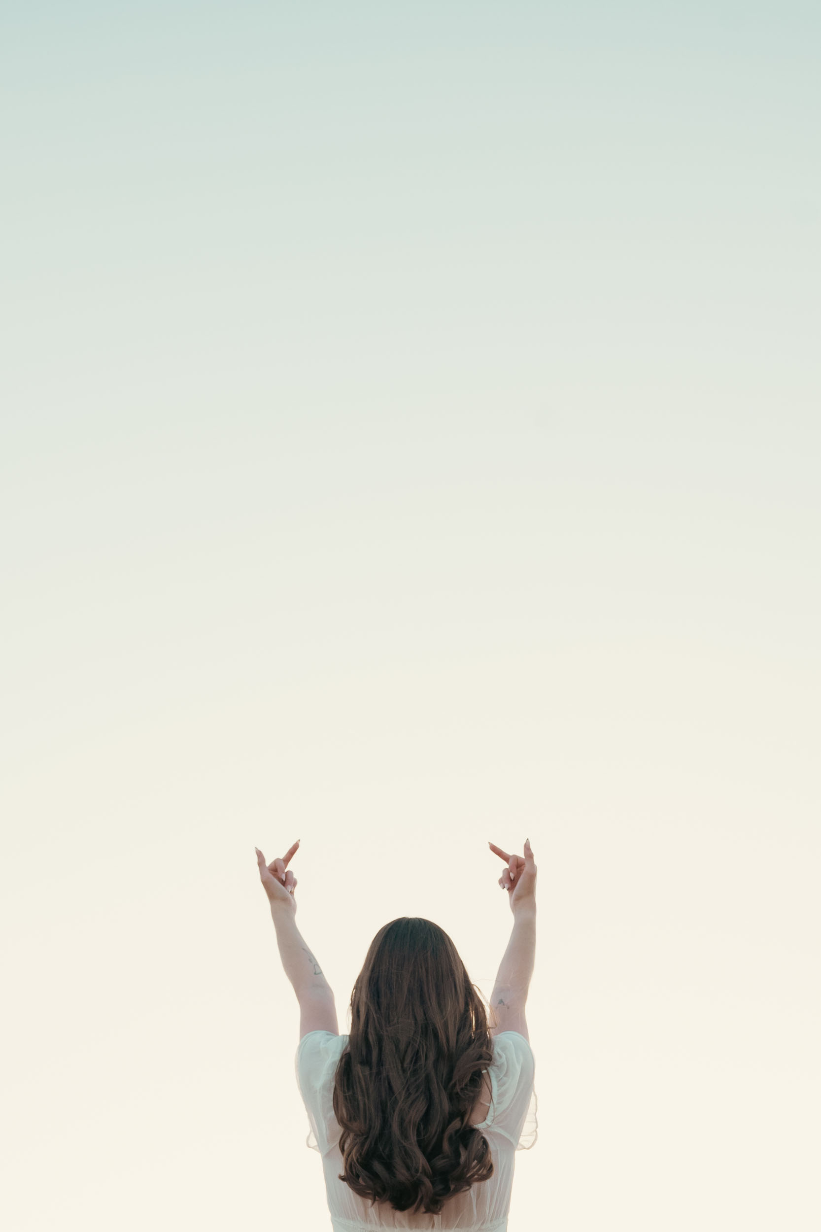 a young woman with middle fingers gesturing to the sky