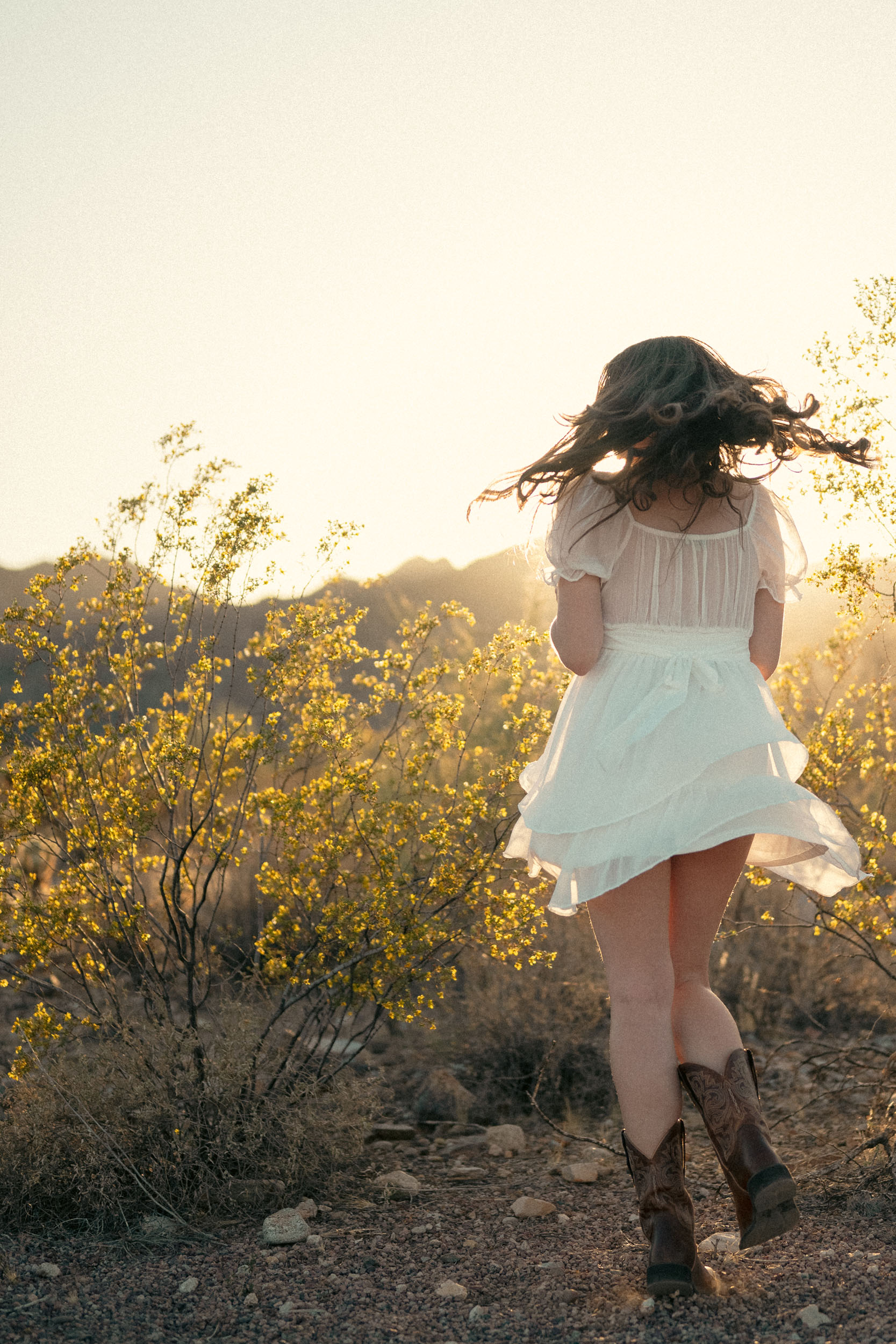 a young woman twirling in a whimsical desert scene at the White Tank Mountains.