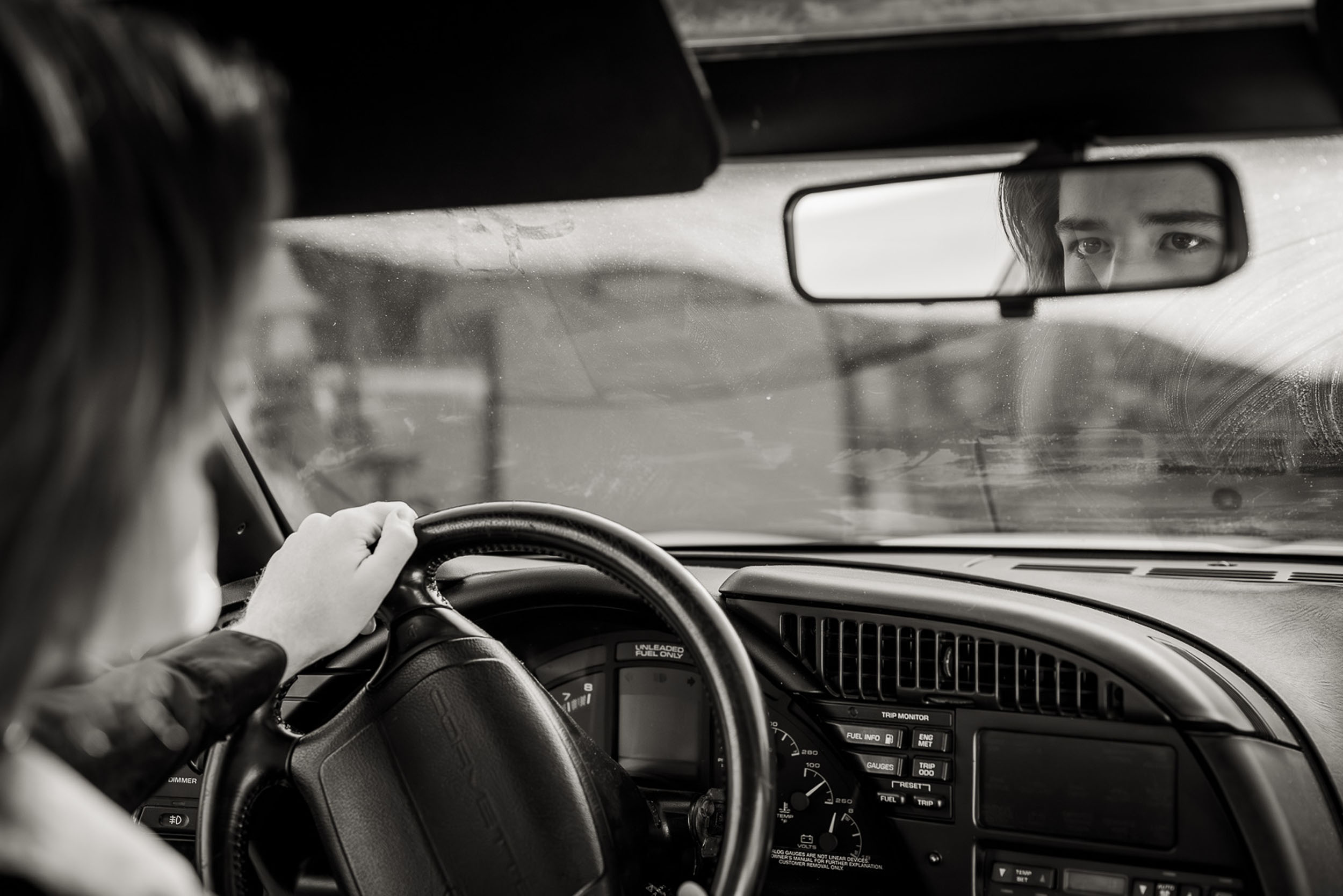 young man looking into the rear view mirror in a classic corvette zr1